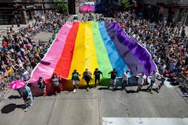 Participants carry a large Pride flag during the Twin Cities Pride Parade on Hennepin Avenue in Minneapolis on Sunday, June 30, 2024.