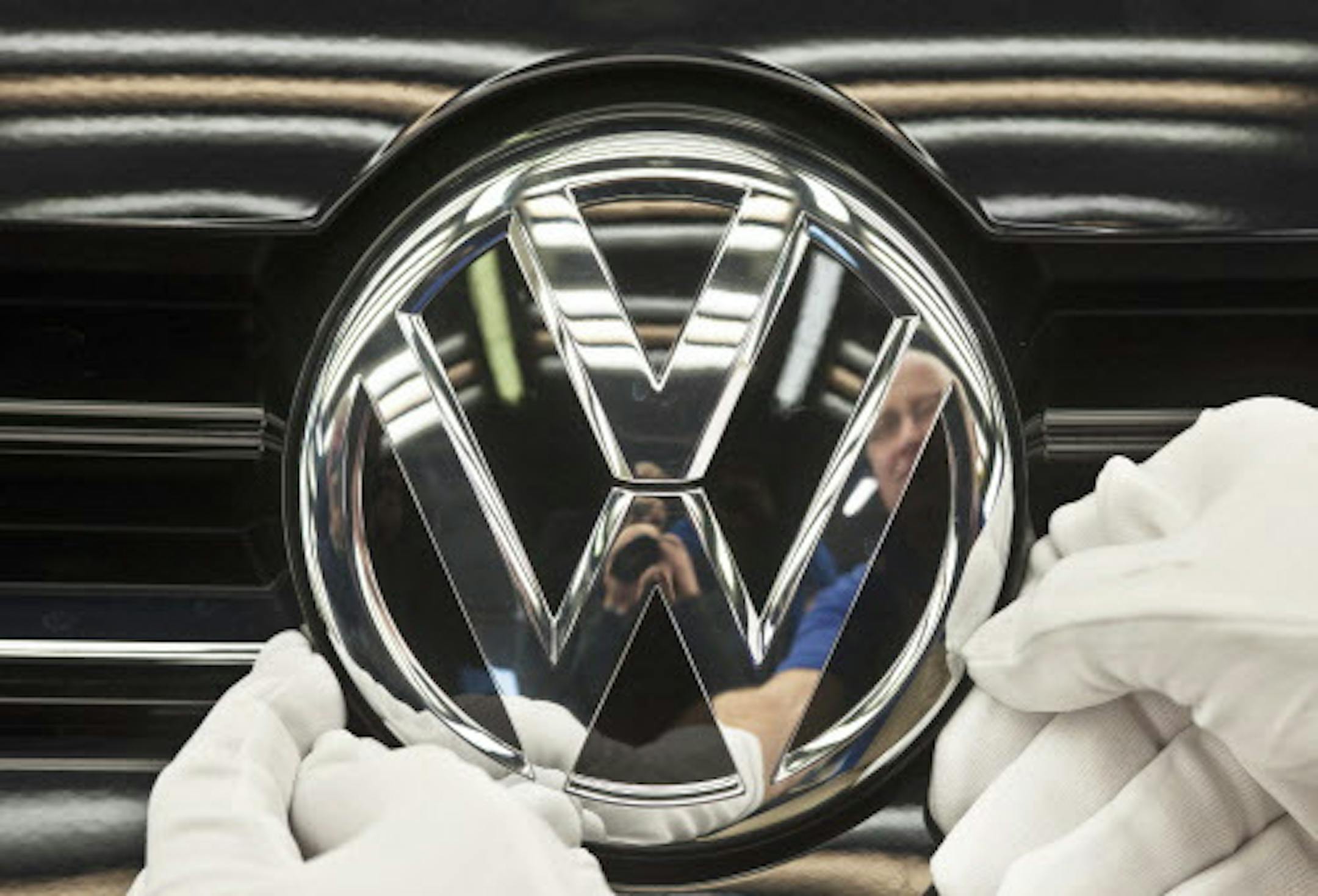 FILE - In this Nov. 9, 2012 file picture a worker fixes a sign at a Volkswagen Golf car during a press tour in Zwickau, central Germany. German automaker Volkswagen AG says its 2012 group sales hit a record high as growing demand around the world more than offset sluggish sales in Europe. It says Monday Jan. 14, 2013 that more than nine million vehicles were delivered for the first time. The total of 9.07 million was up 11.2 percent from the 8.16 million delivered in 2011. (AP Photo/Jens Meyer,F