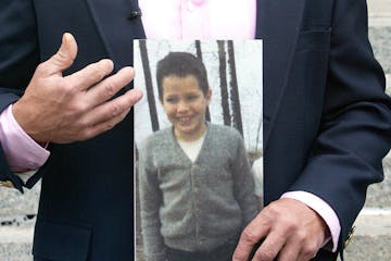 FILE -- Michael DeRoche held a photo of himself at the age of 9 or 10 — the age he was when he says he was abused by a priest in Proctor, Minn.