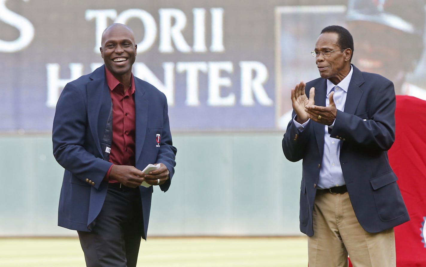 Former Minnesota Twin Rod Carew, right, applauds former outfielder Torii Hunter after Carew presented Hunter his jacket after Hunter's induction into the Twins Hall of Fame on Saturday, July 16, 2016, in Minneapolis. (AP Photo/Jim Mone)