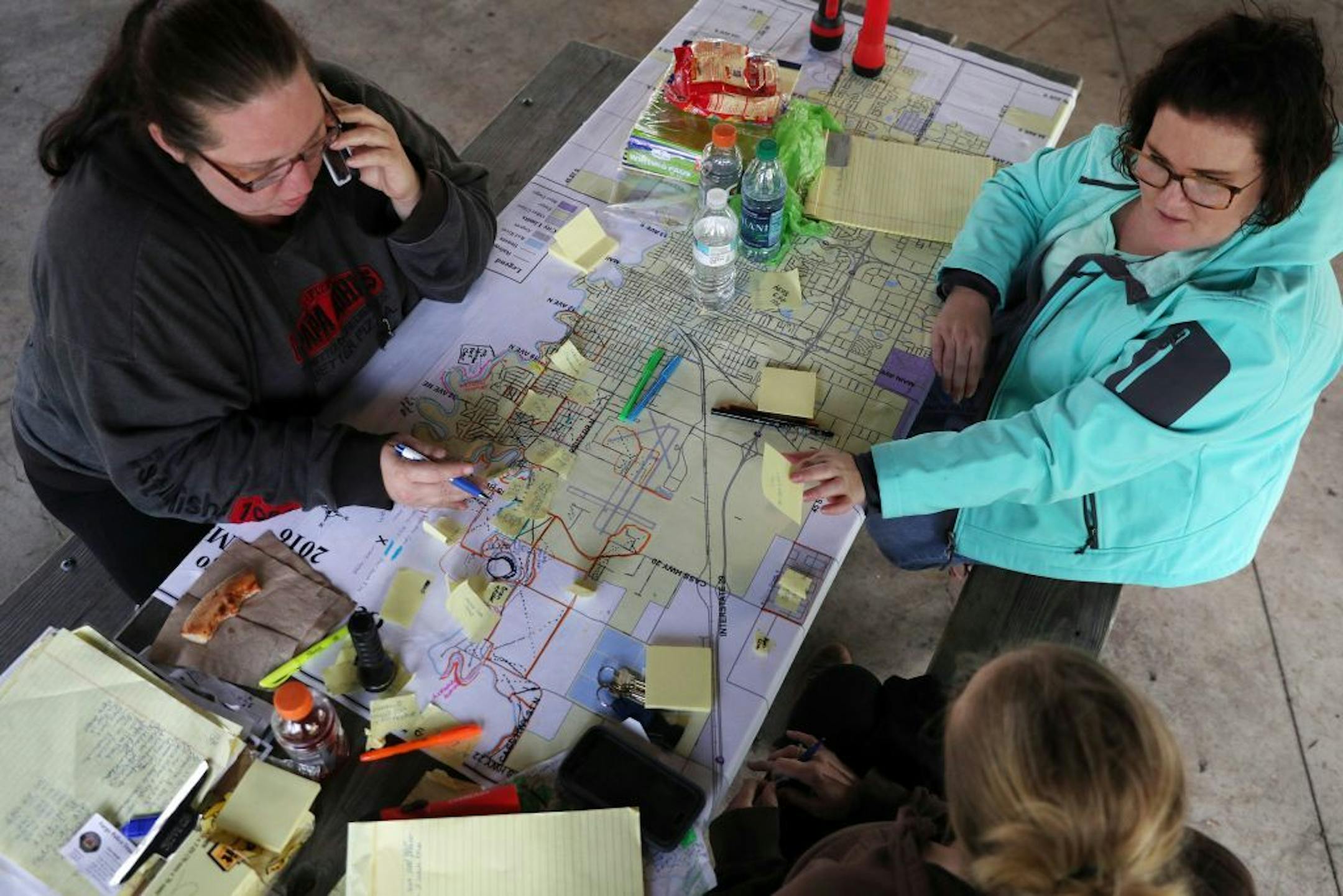 Volunteer search coordinators Christina Becker, left, Julia Wentz, right, and Bekkah Boll, bottom, sat around a map of the city of Fargo as they helped organize the efforts to find Savanna Greywind Saturday afternoon at Trollwood Park in Fargo.