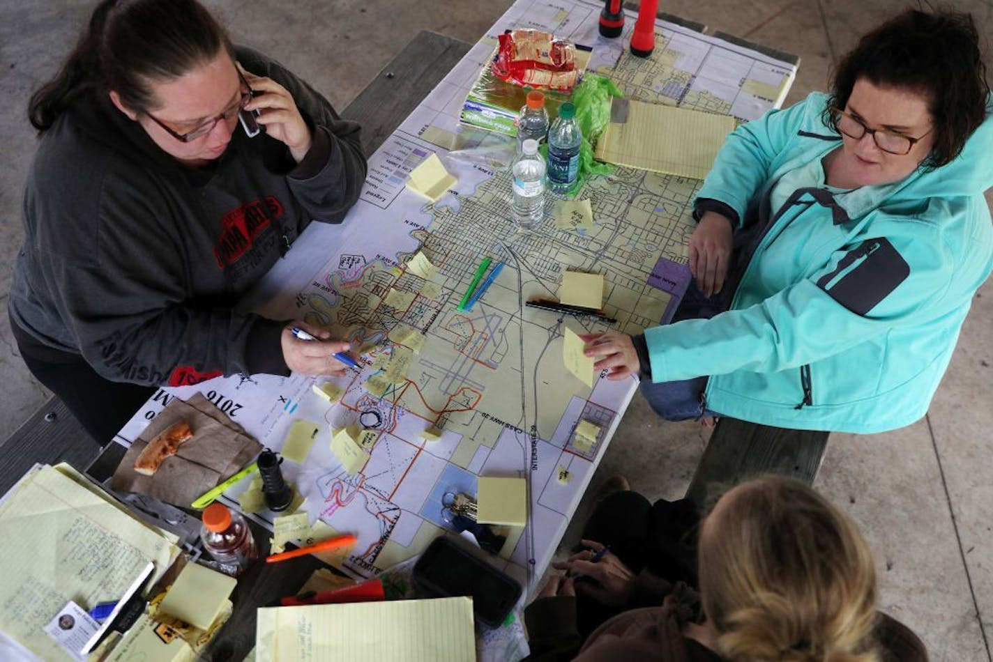 Volunteer search coordinators Christina Becker, left, Julia Wentz, right, and Bekkah Boll, bottom, sat around a map of the city of Fargo as they helped organize the efforts to find Savanna Greywind Saturday afternoon at Trollwood Park in Fargo.