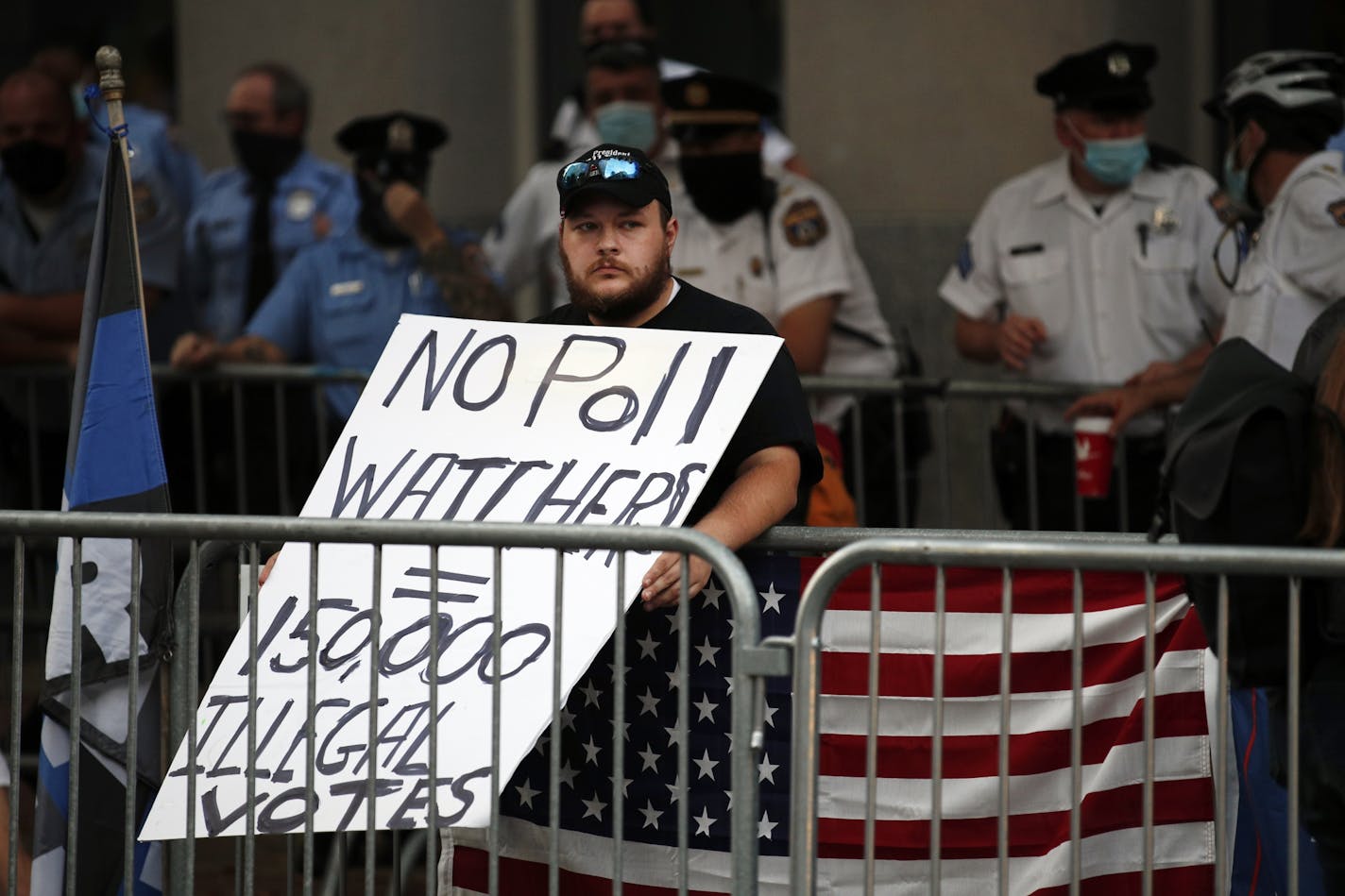 A supporter of President Donald Trump holds a protest sign as police stand guard behind, outside the Pennsylvania Convention Center in Philadelphia, Sunday, Nov. 8, 2020, a day after the 2020 election was called for Democrat Joe Biden.