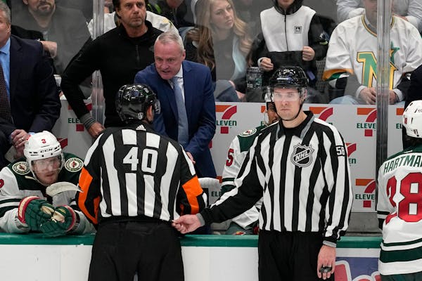 Coach Dean Evason talked from behind the Wild bench with referee Steve Kozari (40) and linesman Ryan Gibbons (58) late in the third period of Game 5 i