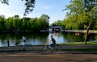 A cyclist passes Lake of the Isles Lagoon and Canal May 15, 2023, in Minneapolis.
