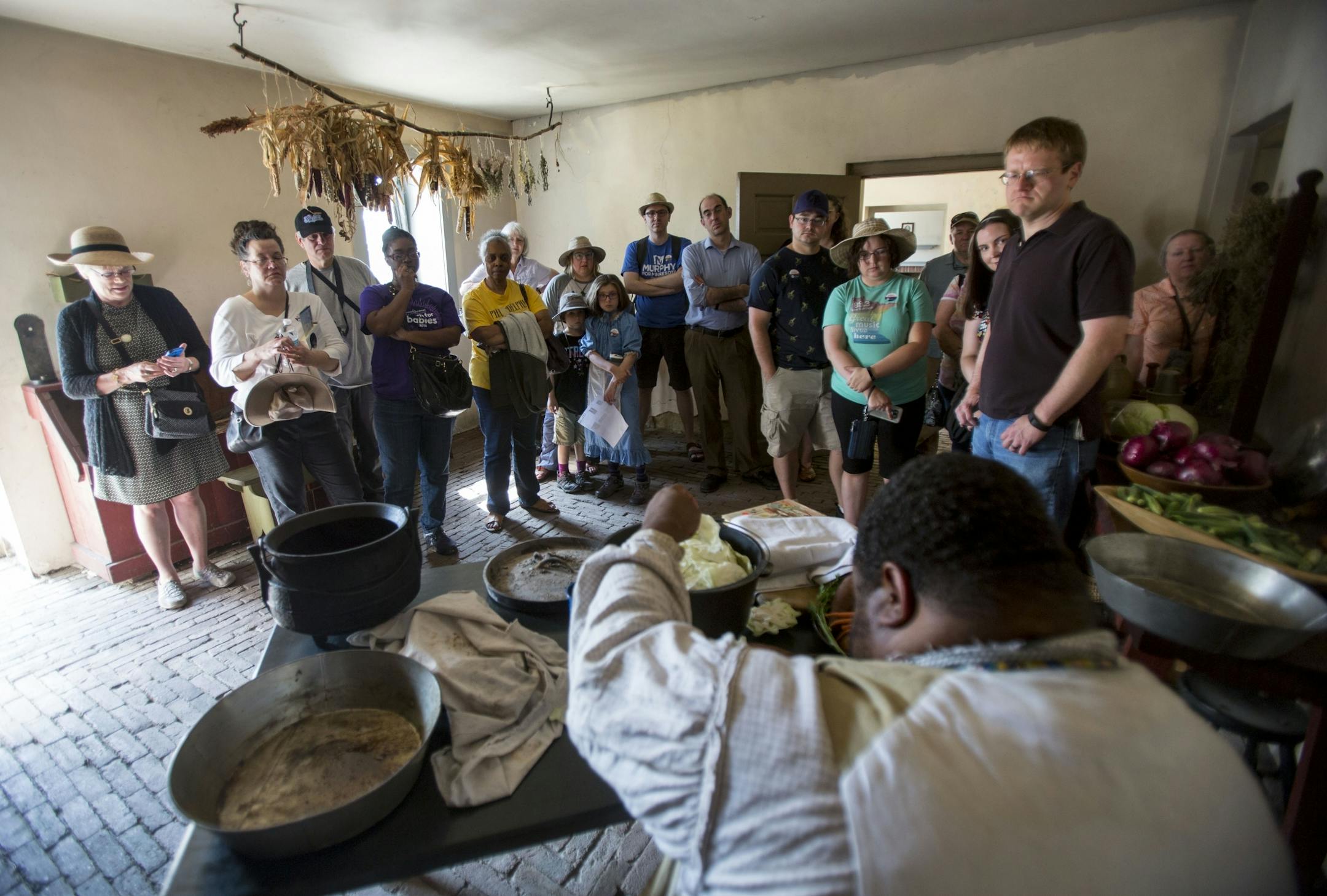 Michael Twitty covers the chicken with cabbage leaves as visitors watch and listen.