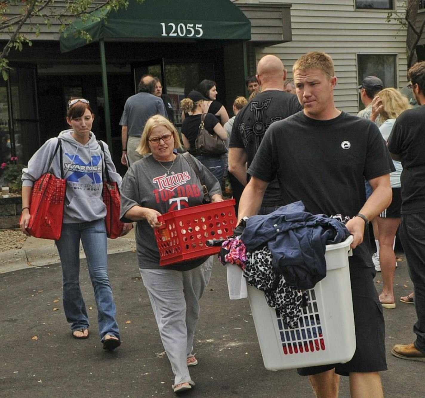 Lucas Peterson along with his mother, Debbie Peterson, and Kristine Michael carry some of his mother's clothes and other belongings from her apartment. Debbie Peterson's apartment had heavy smoke damage, but she expects to move back in in a couple of days. A fire heavily damaged the Parkside Apartments in Plymouth early Friday.Fire officials say one of the three apartment buildings at Parkside Apartments was fully engulfed when they arrived on the scene just after 1 a.m.