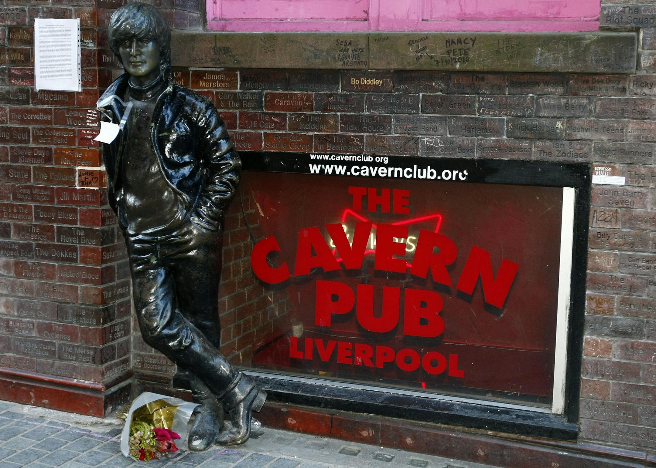 A note and flowers left at a statue of John Lennon outside the Cavern Pub in Mathew Street, Liverpool, England, Wednesday Dec. 8, 2010. Beatles fans will mark the 30th anniversary of John Lennon's death with a candlelit vigil at the city's European Peace Monument, which is dedicated to John Lennon. (AP Photo/Tim Hales)