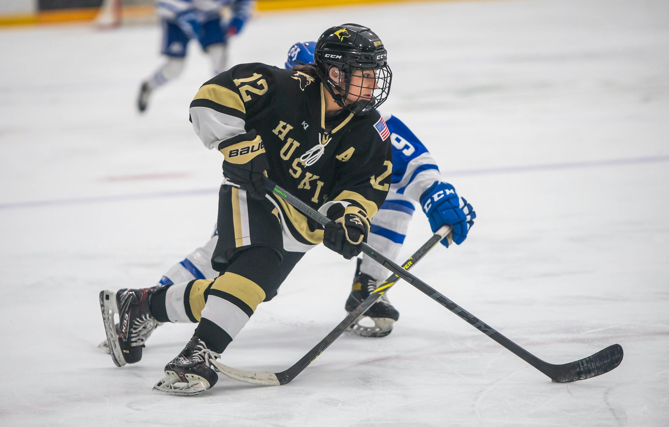 Andover's Isa Goettl (12) controls the puck against a Minnetonka defender during the championship game of the Walser Invitational.