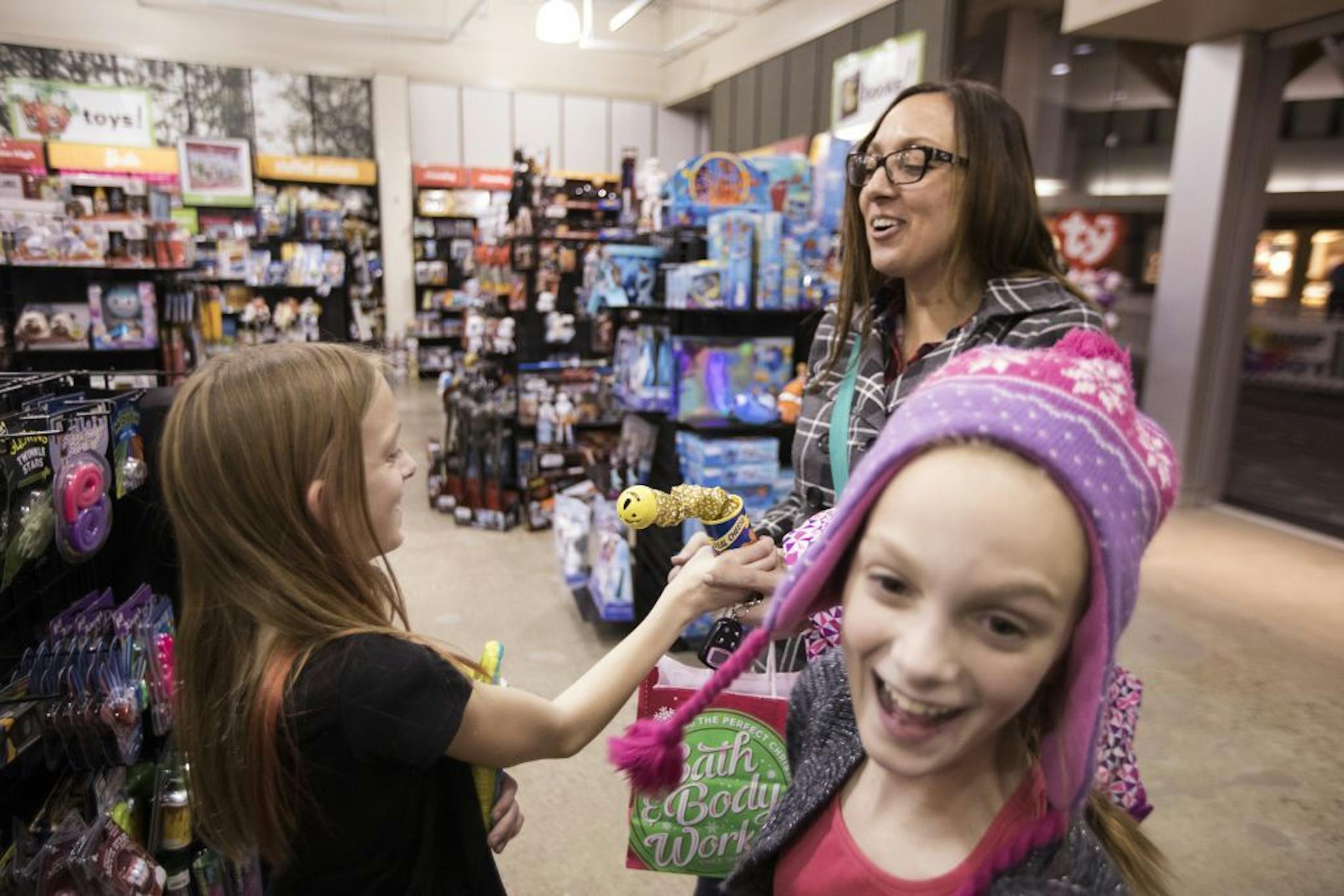 Isabelle, right, and Abby Carlsen play a gag on their mother, Amy, while Christmas shopping with their parents at Kirkland Mall in Bismarck.
