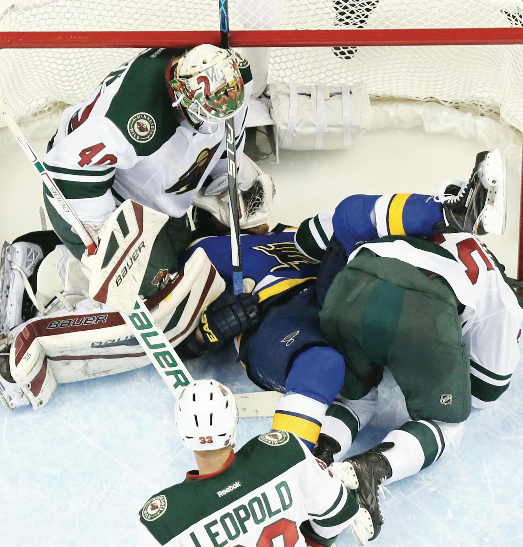 St. Louis Blues center Steve Ott falls over Minnesota Wild defenseman Matt Dumba in the crease during the second period of Game 5 of a first-round NHL hockey playoff series Friday, April 24, 2015, in St. Louis. At left is Wild goaltender Devan Dubnyk. (Chris Lee/St. Louis Post-Dispatch via AP)