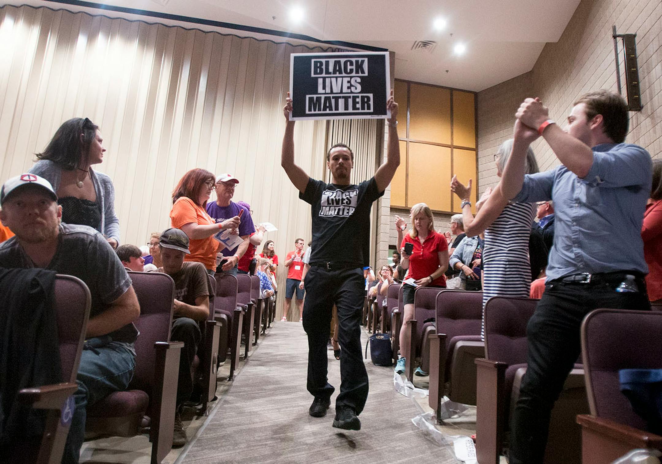 Jaylin Gratsy holds up a Black Lives Matter sign as he leads students onto the stage.