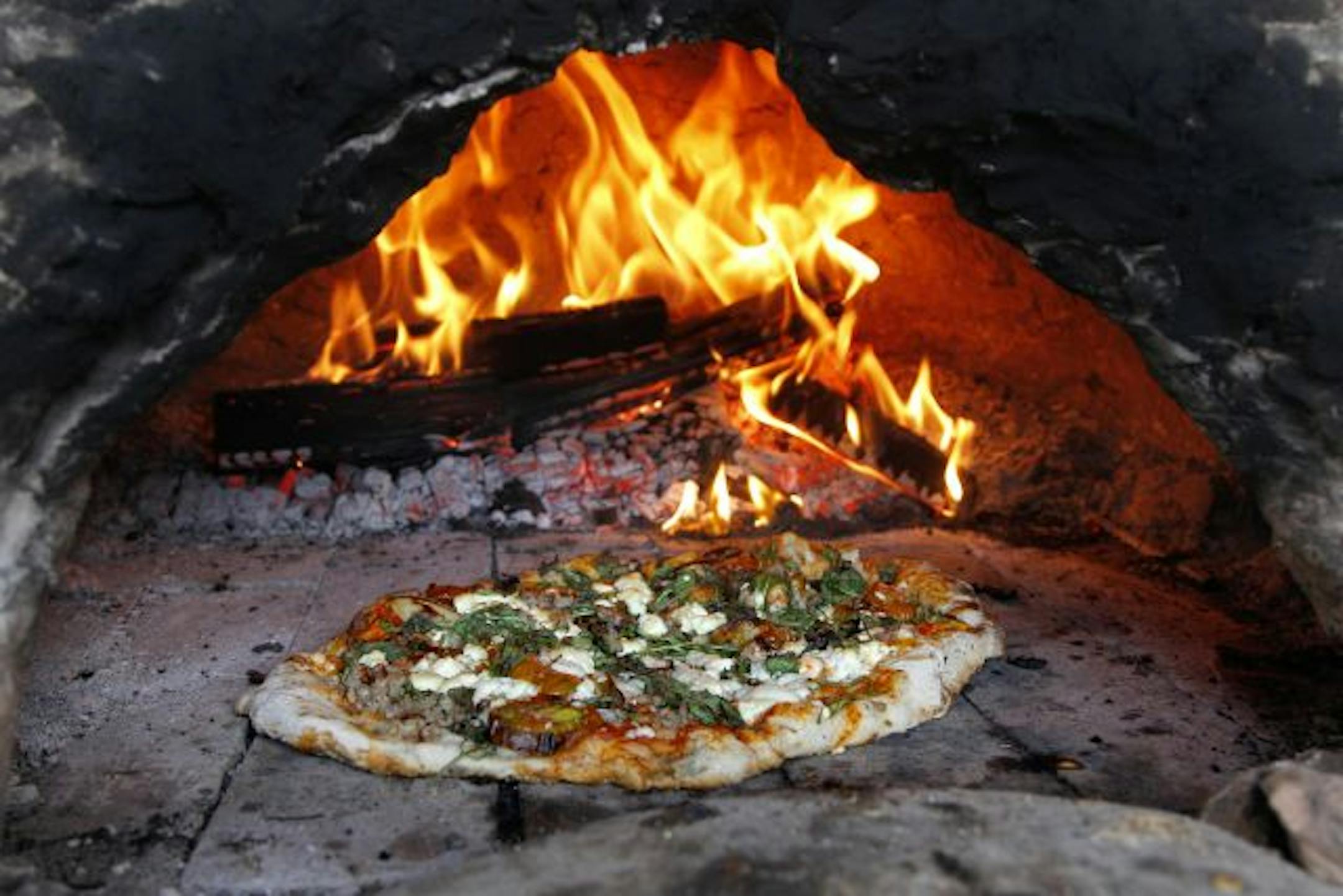 Maple and elm logs, harvested from the farm, fuel the fire in the pizza oven.