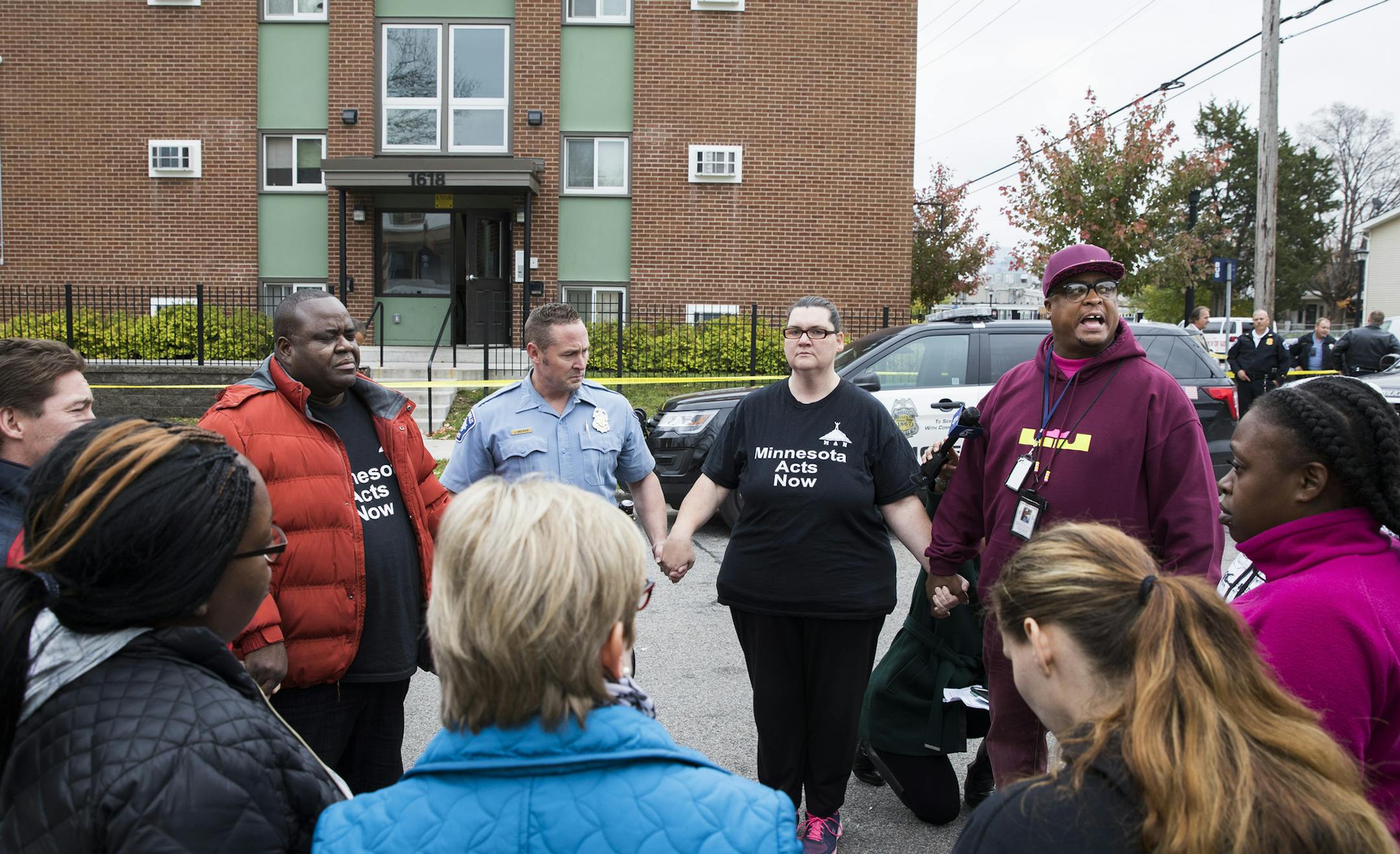 Community anti-violence activist K.G. Wilson, at right in maroon hat and sweatshirt, says a few words during a prayer with other community members outside the scene of a homicide in Minneapolis. ] (Leila Navidi/Star Tribune) leila.navidi@startribune.com BACKGROUND INFORMATION: The scene of a homicide at Glenwood and N. Knox Avenues in Minneapolis on Thursday, October 27, 2016. A man was found shot to death Thursday morning in his north Minneapolis apartment in what police are classifying as homi