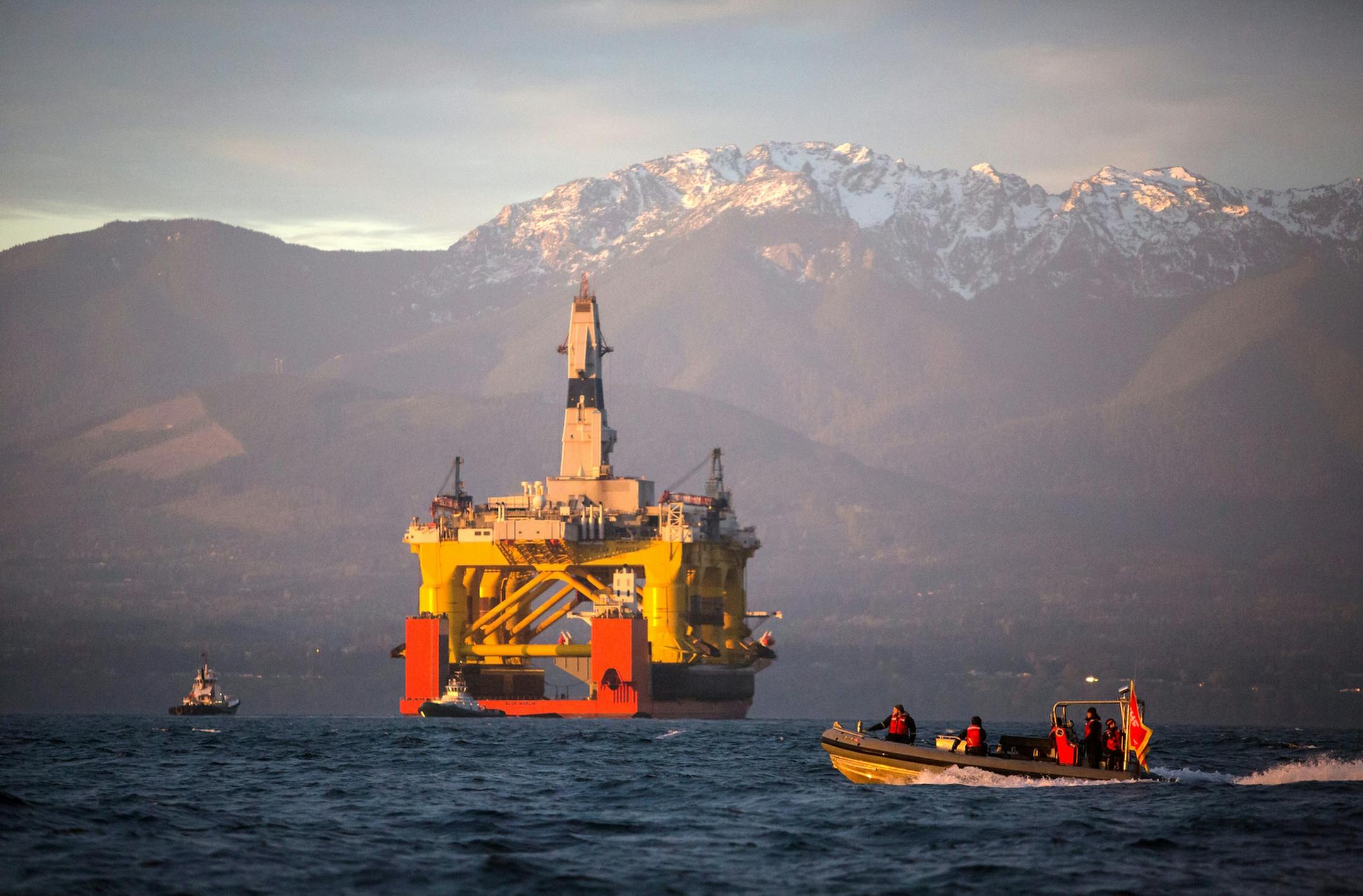 FILE - In this April 17, 2015 file photo, with the Olympic Mountains in the background, a small boat crosses in front of the Transocean Polar Pioneer, a semi-submersible drilling unit that Royal Dutch Shell leases from Transocean Ltd., as it arrives in Port Angeles, Wash., aboard a transport ship after traveling across the Pacific before its eventual Arctic destination. The U.S. government on Monday gave Shell the final permit it needs to drill for oil in the Arctic Ocean off Alaska's northwest