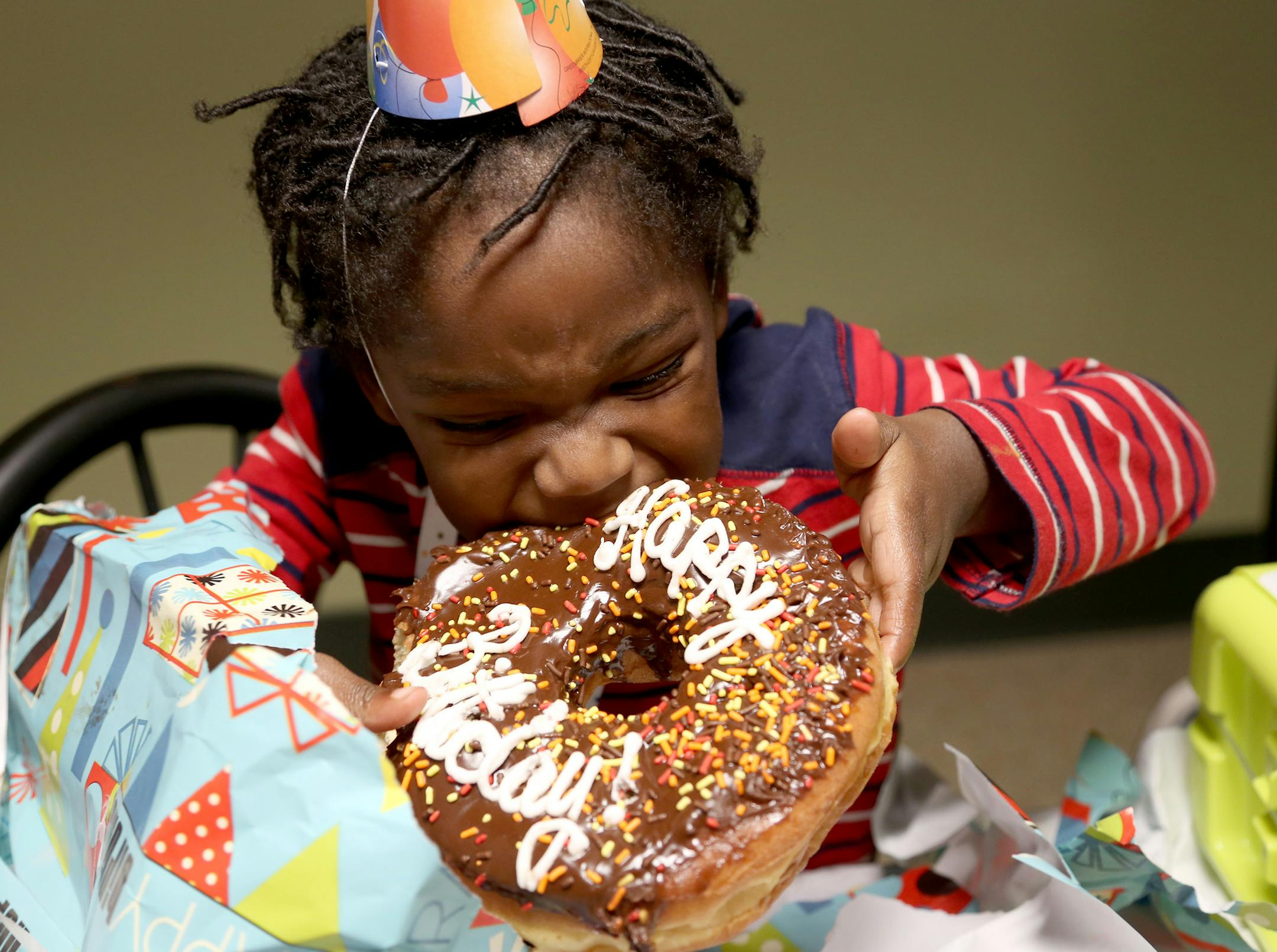 Carlyle Gaithers, 4, took a bite out of his birthday doughnut during a birthday party for November birthdays at People Serving People as a party of the Birthday Project. ] (KYNDELL HARKNESS/STAR TRIBUNE) kyndell.harkness@startribune.com Birthday party for homeless children whose birthdays are in November at People Serving People in Minneapolis Min., Thursday November 13, 2015.The Birthday Party Project is hosting birthday parties for the children living in People Serving People.