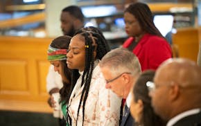 Minister JaNaƩ Bates prays with other faith leaders during an interfaith service at City Hall in Minneapolis on Friday for the four-year anniversary