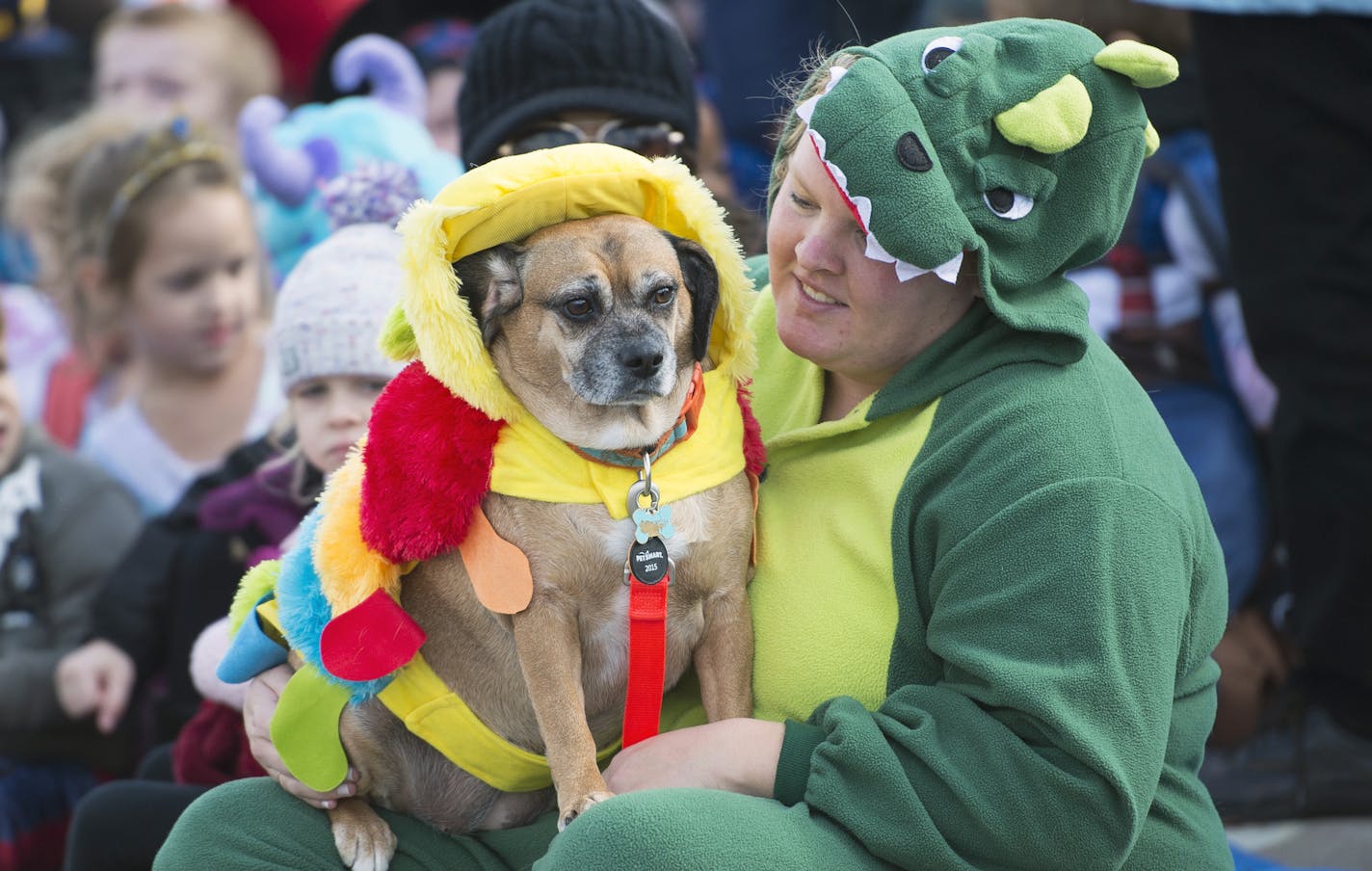 Kayla Bergerson , dressed as a dinosaur, sits with her dog piper, dressed as a caterpillar, before the start of a Halloween parade, Friday, Oct. 30, 2015 in Anoka, Minn. (Aaron Lavinsky/Star Tribune via AP) MANDATORY CREDIT; ST. PAUL PIONEER PRESS OUT; MAGS OUT; TWIN CITIES LOCAL TELEVISION OUT