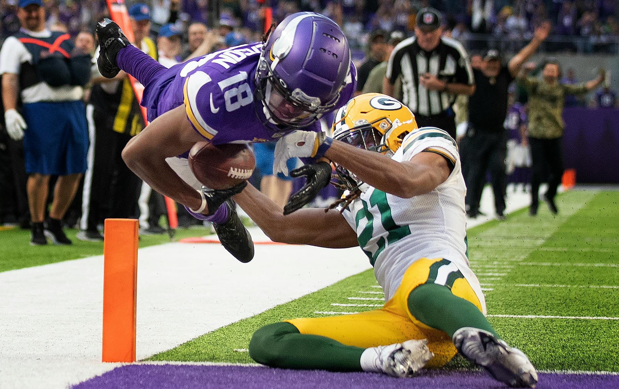 Minnesota Vikings wide receiver Justin Jefferson ,(18) dives in the end-zone for a 23 yard touchdown over Green Bay Packers cornerback Eric Stokes ,(21) in the fourth quarter.