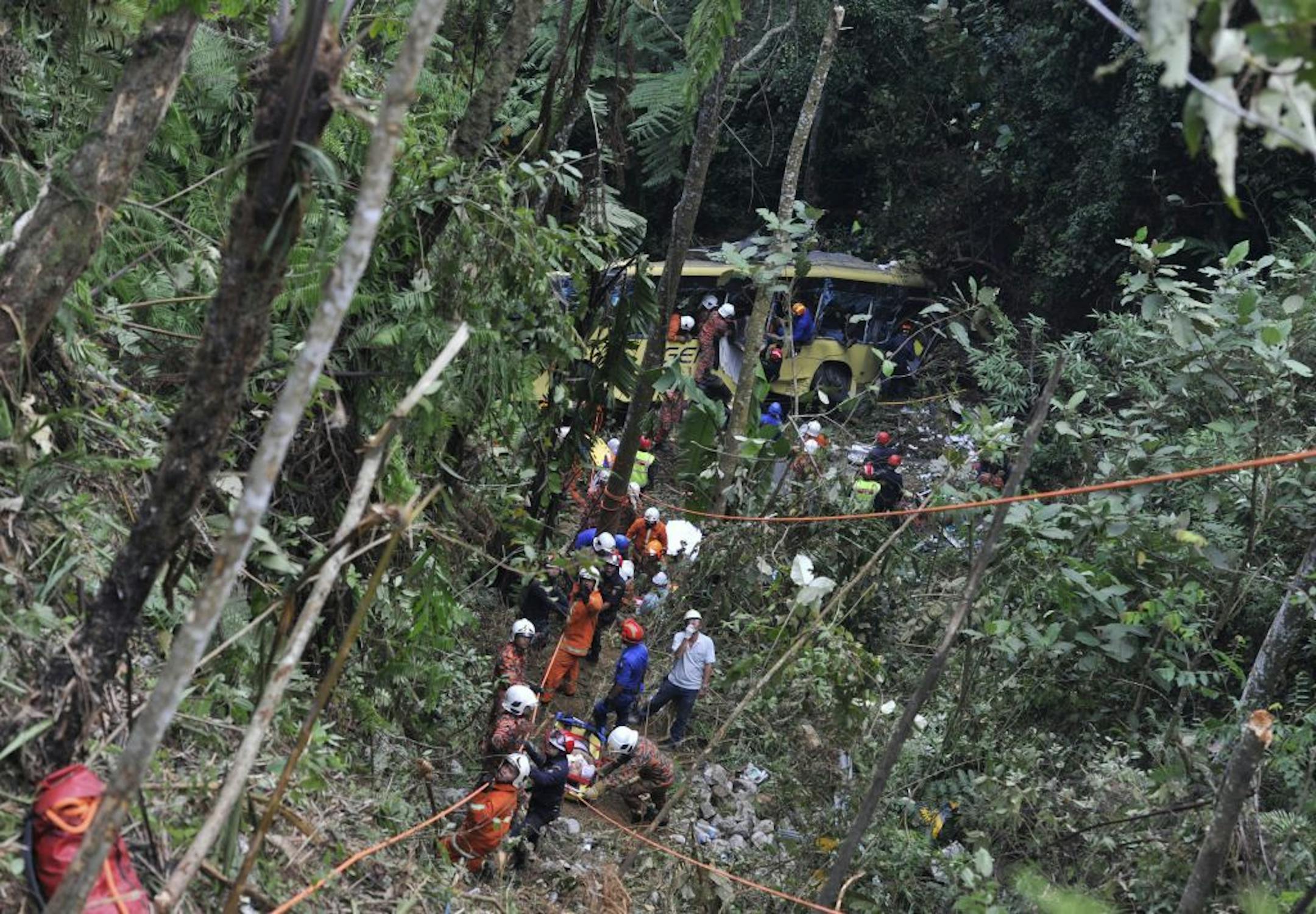 Malaysian emergency services personnel rescue a passenger, seen bottom on a stretcher, after a passenger bus carrying tourists and local residents fell into a ravine near the Genting Highlands, about an hour's drive from Kuala Lumpur, Malaysia, Wednesday, Aug. 21, 2013.