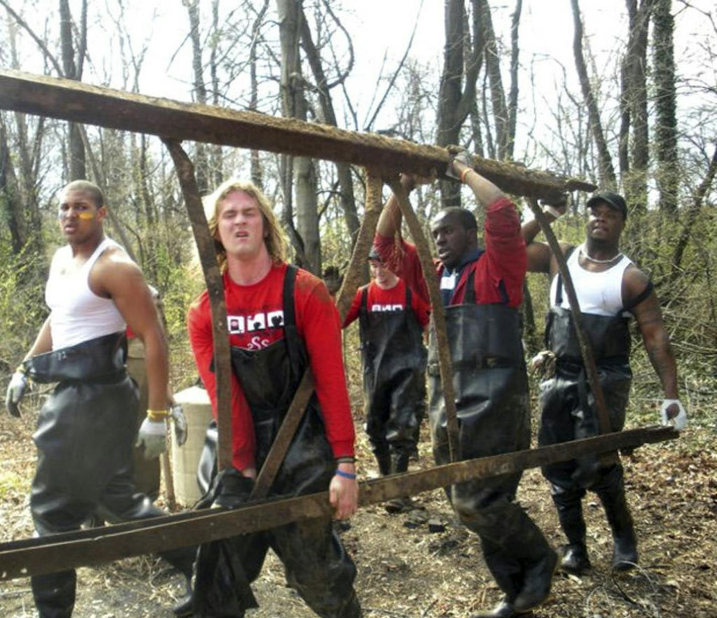 Gopher football team members D.L. Wilhite ( front, left, white shirt) and Brandon Kirksey (back, white shirt) participate in a clean-up project as part of a summer tour.