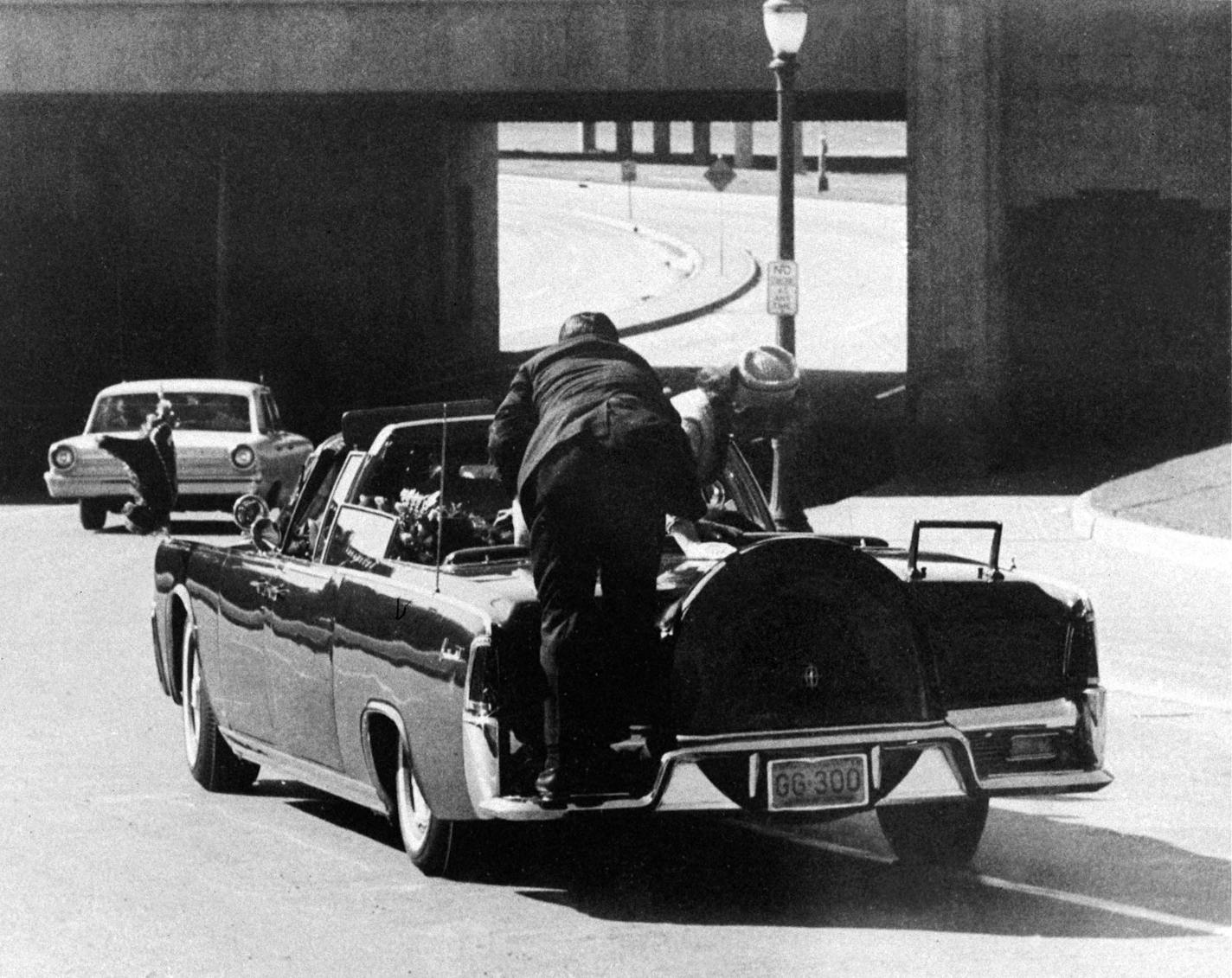 FILE - In this Nov. 22, 1963 file photo, President John F. Kennedy slumps down in the back seat of the Presidential limousine as it speeds along Elm Street toward the Stemmons Freeway overpass after being fatally shot in Dallas. Mrs. Jacqueline Kennedy leans over the president as Secret Service agent Clinton Hill rides on the back of the car. (AP Photo/Ike Altgens, File) ORG XMIT: TXKJ307