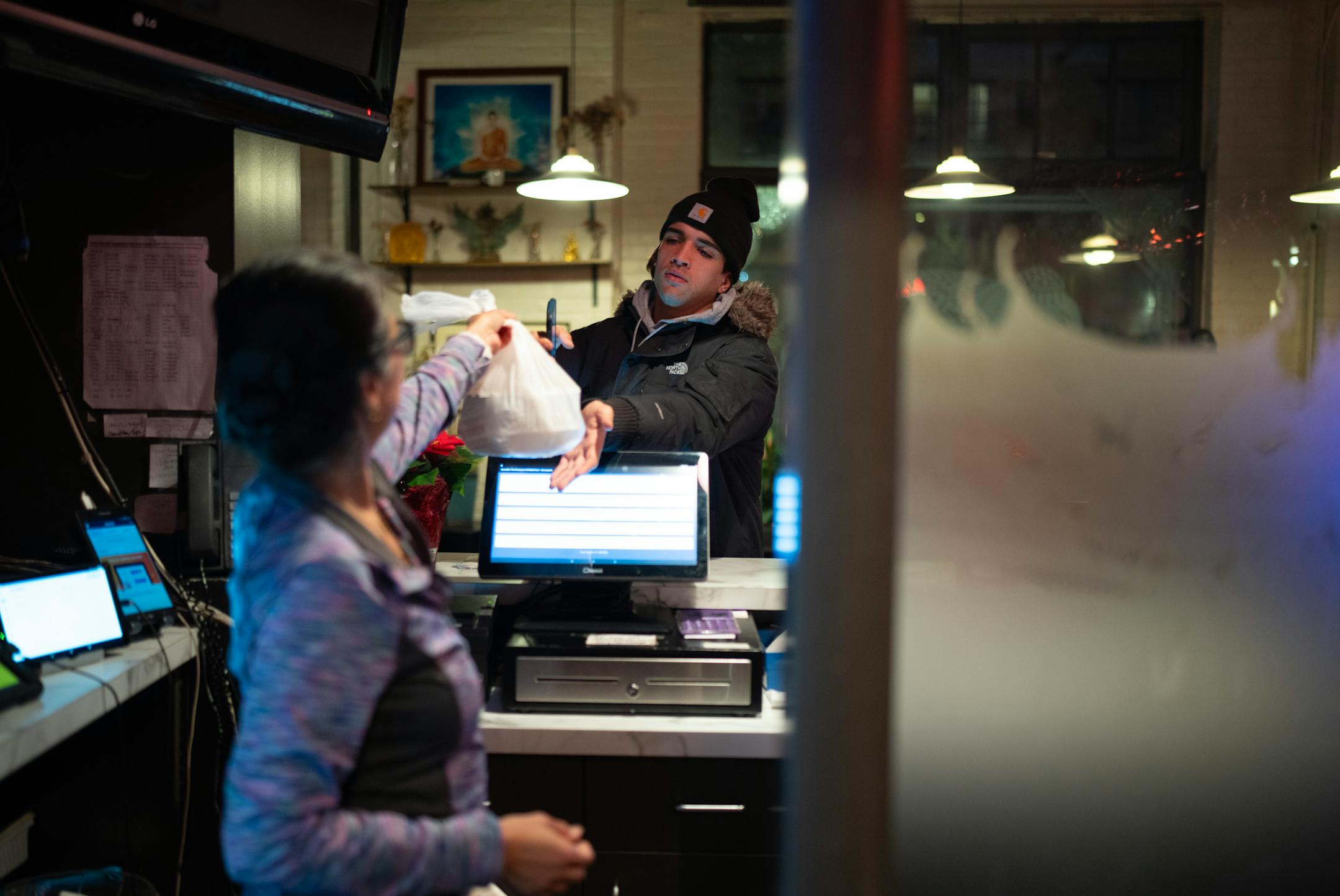 Sam Simonson handed a takeout order to a DoorDash delivery person at Sawatdee in Minneapolis Thursday night, December 14, 2023. Third party delivery food delivery services are a growing share of business at fast food restaurants and for other restaurants with cuisines that travel well like the Thai menu at Sawatdee in Minneapolis, where they account for 30% of their business. ] JEFF WHEELER • Jeff.Wheeler@startribune.com