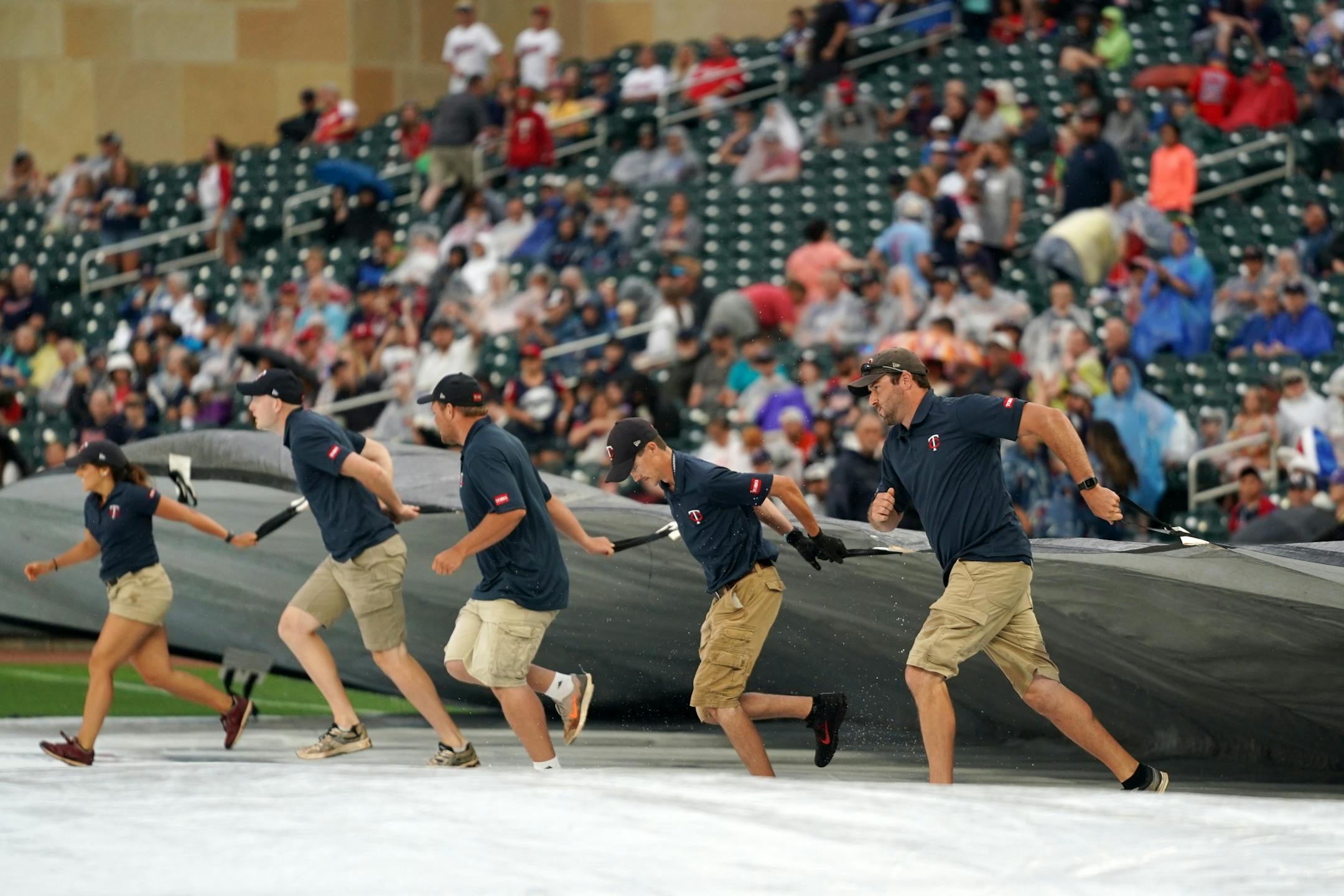 Members of the grounds crew removed the tarp from the infield following rain delay Friday at Target Field.