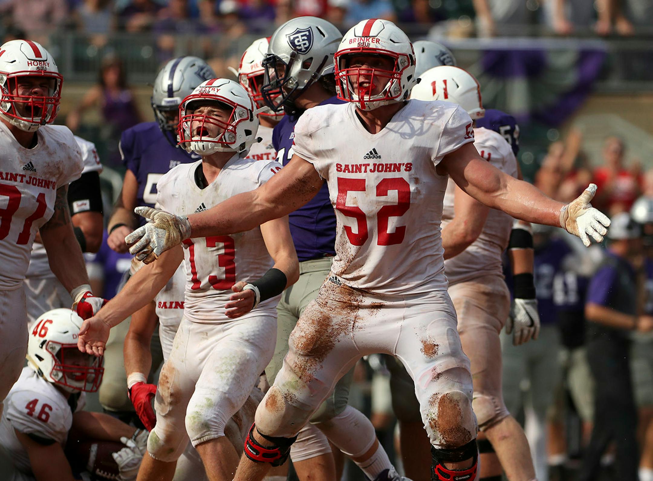 St. John's University defensive lineman Nathan Brinker (52) celebrated after University of St. Thomas running back Josh Parks (26) was pulled down by St. John's University defensive lineman Trevor Dittberner (46) in the second half.