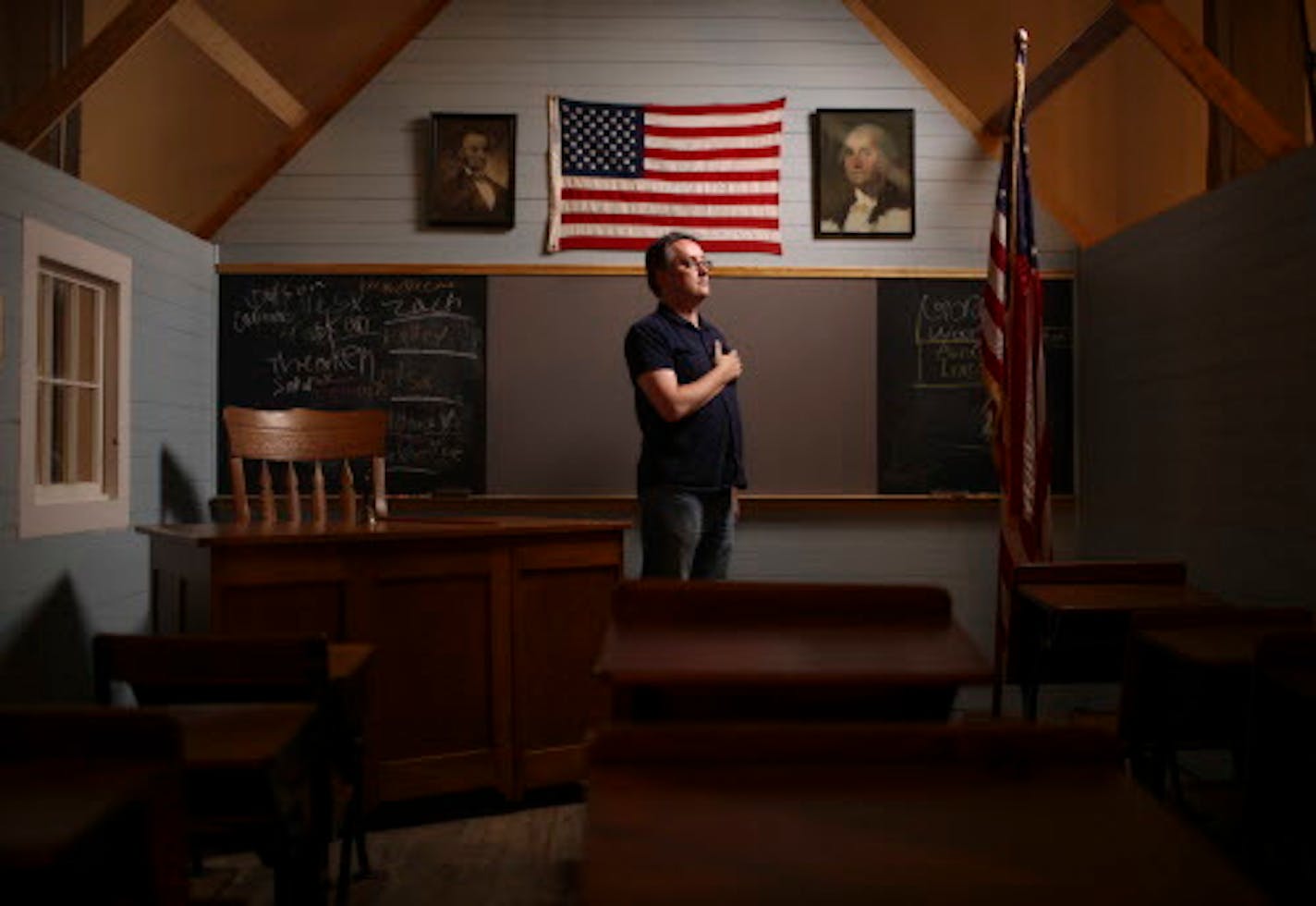 Ben Heywood in the installation "Pledge Project" at The Soap Factory Monday afternoon. The piece, by artists Shana Berger and Nathan Purath, explores the ritual of the Pledge of Allegiance. They recreated a one room schoolhouse based on the historic Perault School near Red Lake Falls, which Purath's grandfather attended in the 1920's.   ]   JEFF WHEELER • jeff.wheeler@startribune.com     The Soap Factory's Executive Director Ben Heywood is donning a curator's hat for "Americana," a look at American politics and culture through 3 videos, 4 installations, and a photo project by nine emerging artists. The show is the British-born curator's effort to assess "the assumptions and stereotypes of this mythic land, my adopted home."