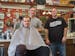 Pete Klein, center, and Mark Kern, right, co-owners of 7th Street Barbers, with a customer in the chair.