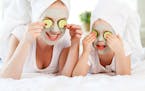 Happy family mother and child daughter make face skin mask with towel on head