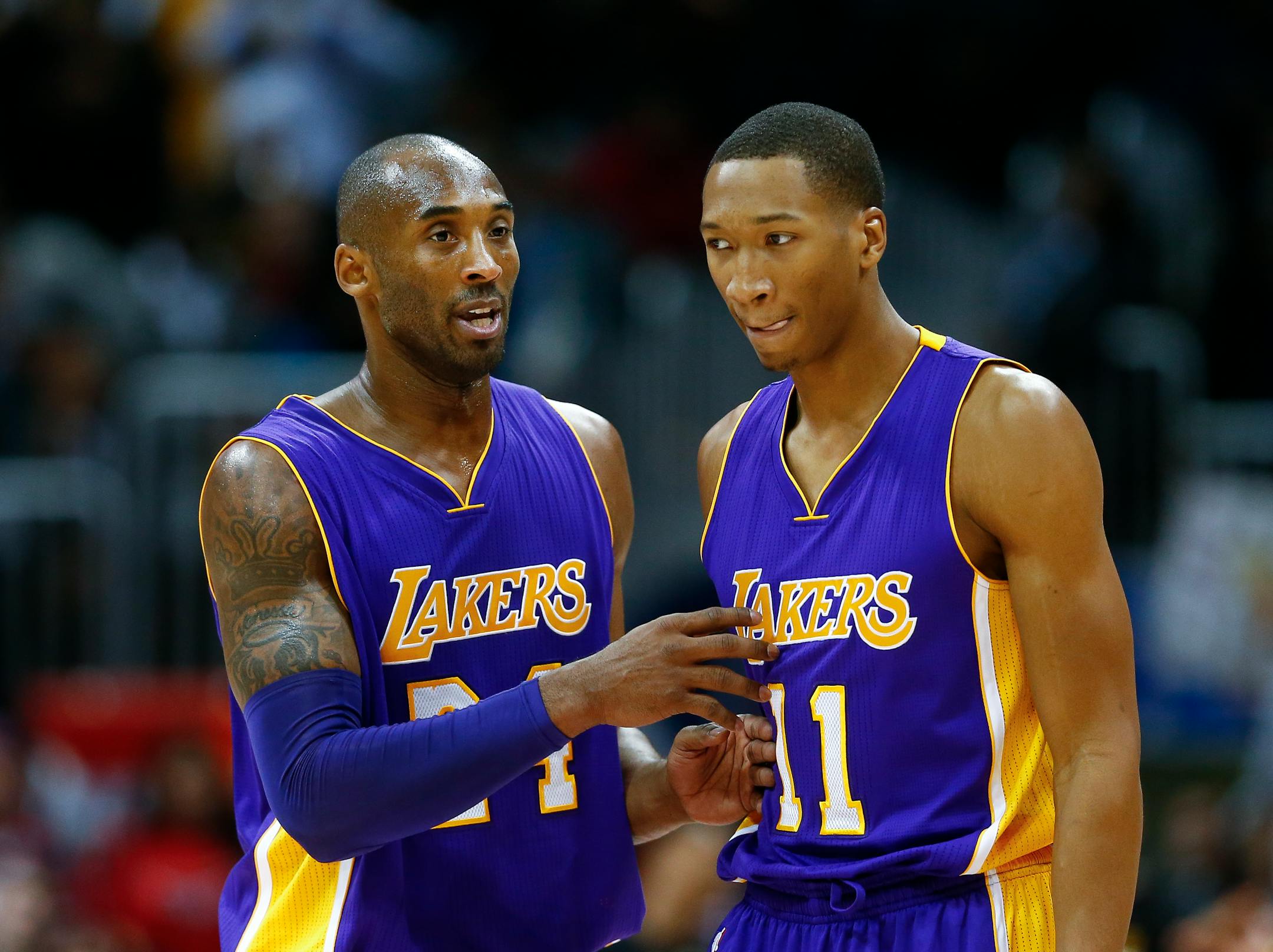 Los Angeles Lakers guard Kobe Bryant (24) talks with teammate Wesley Johnson (11) in the first half of an NBA basketball game Tuesday, Nov. 18, 2014, in Atlanta. (AP Photo/John Bazemore)