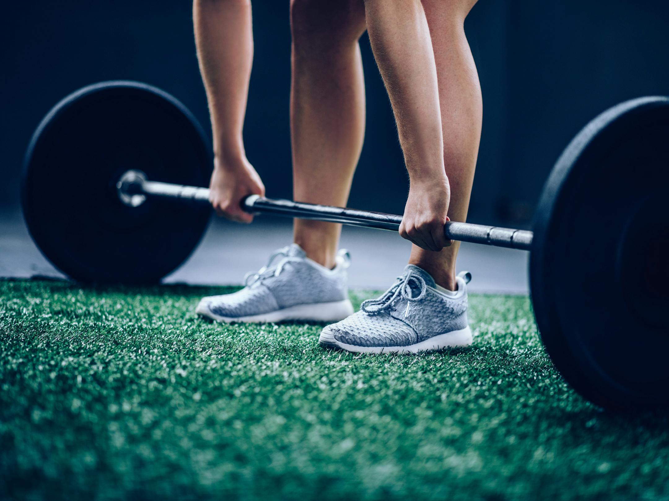 Fit Girl picking up heavy barbell with weights for workout