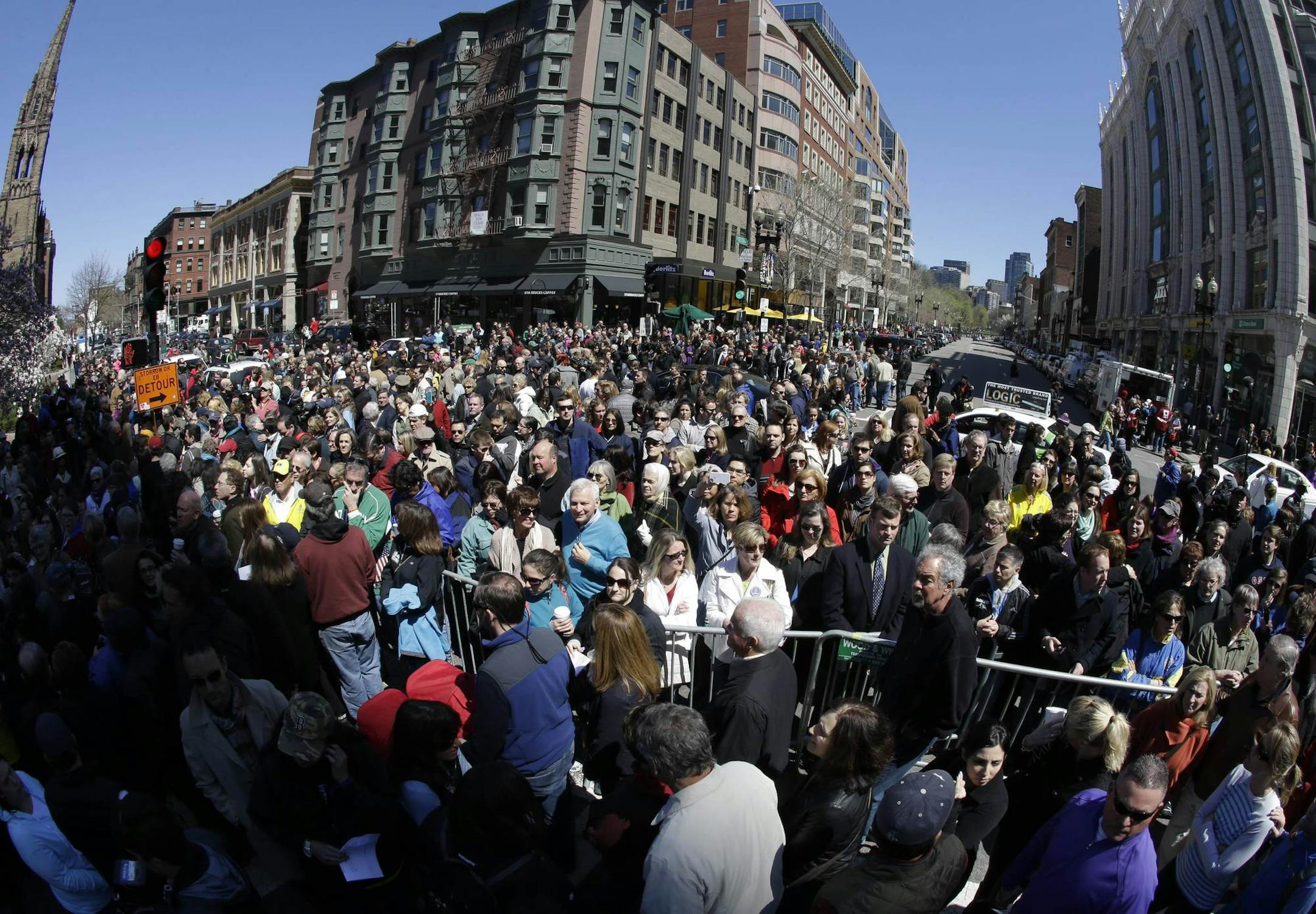 In this photograph made with a fisheye lens, people attend an interfaith service held near a makeshift memorial on Boylston Street, near the finish line of the Boston Marathon, Sunday, April 21, 2013, in Boston. The city is coping in the aftermath of the marathon bombing. (AP Photo/Julio Cortez)