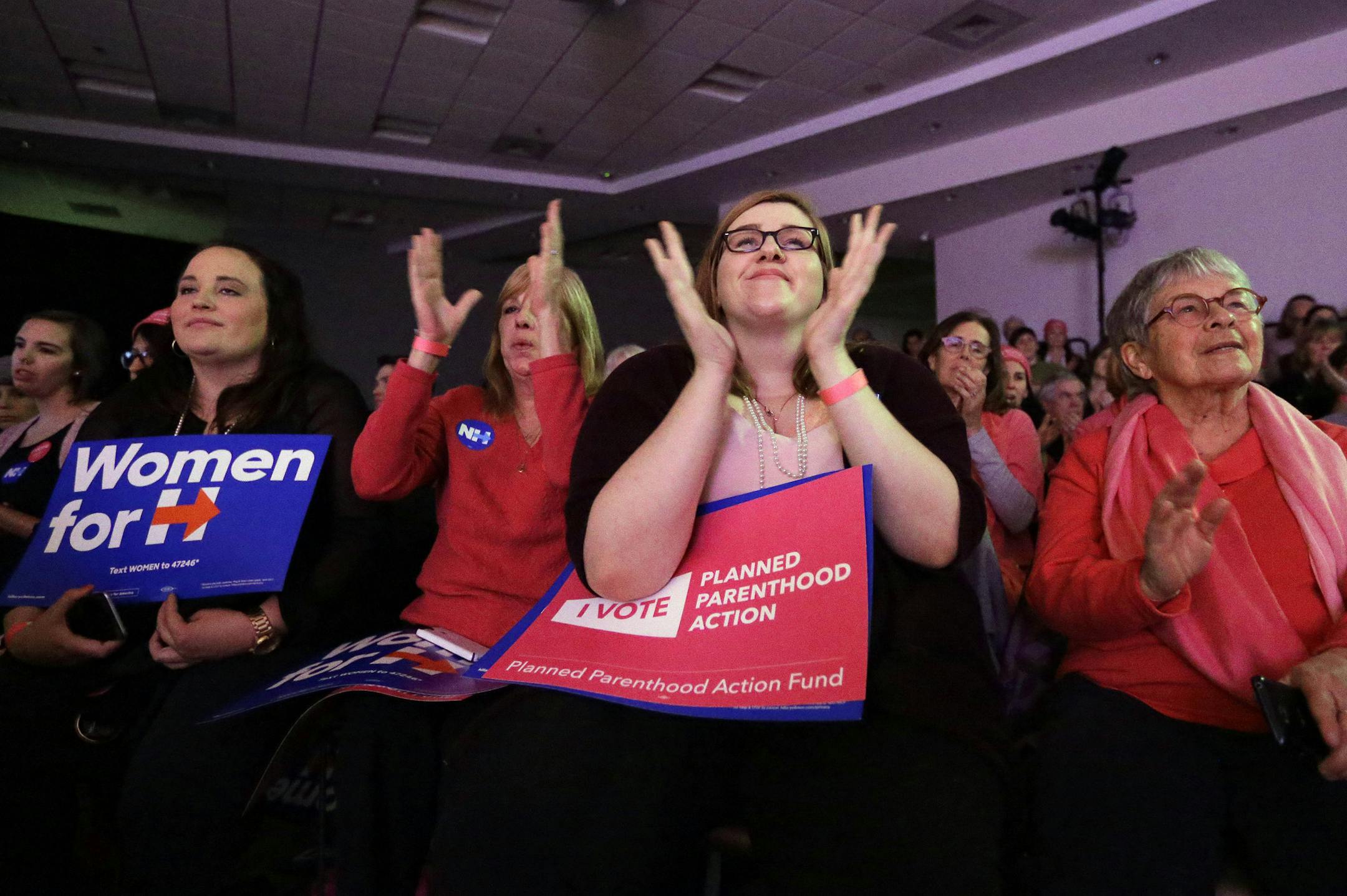Women in the audience hold placards and clap in an event Sunday, Jan. 10, 2016, in Hooksett, N.H., during which Democratic presidential candidate Hillary Clinton was endorsed by Planned Parenthood. The endorsement by the group's political arm marks Planned Parenthood's first time wading into a presidential primary. (AP Photo/Steven Senne)