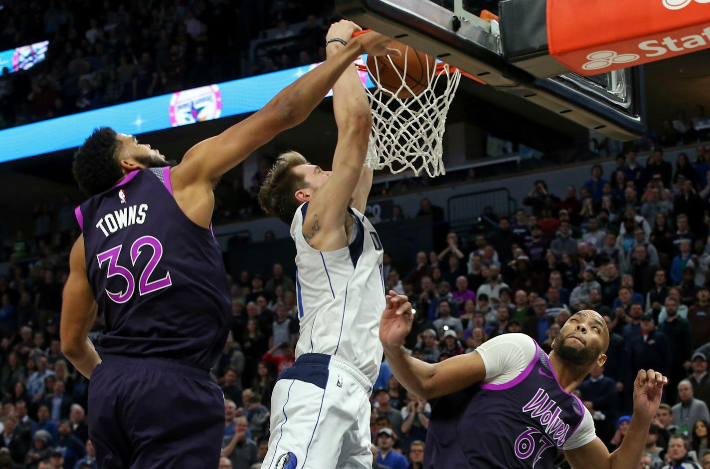 Dallas Mavericks' Luka Doncic, center, of Slovenia, dunks as Minnesota Timberwolves' Karl-Anthony Towns, left, defends and Taj Gibson, right, watches in the second half of an NBA basketball game Friday, Jan. 11, 2019, in Minneapolis. (AP Photo/Jim Mone)