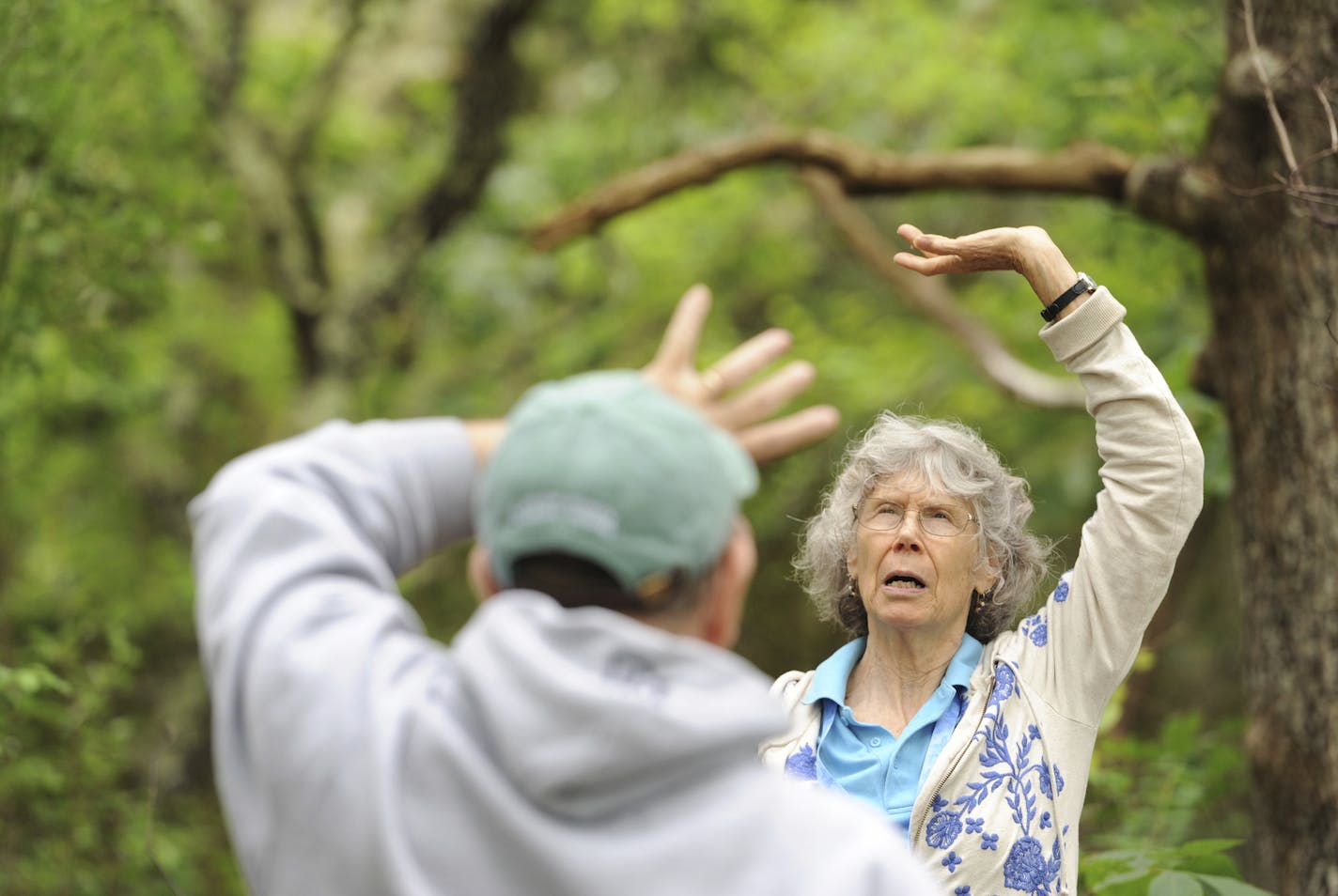 In this June 19, 2019 photo, Carol Marcy leads the group in a breathing exercise during a stop on the walking trails behind the Cape Cod Museum of Natural History in Brewster, Mass. Marcy leads a series of meditative nature walks called "forest baths" that is a part of a Japanese practice called Shinrin-yoku. She lead a small group through the trails behind the Cape Cod Museum of Natural History. (Merrily Cassidy/The Cape Cod Times via AP) ORG XMIT: MER72748682d4518ba44dd7c1ac4b2d1