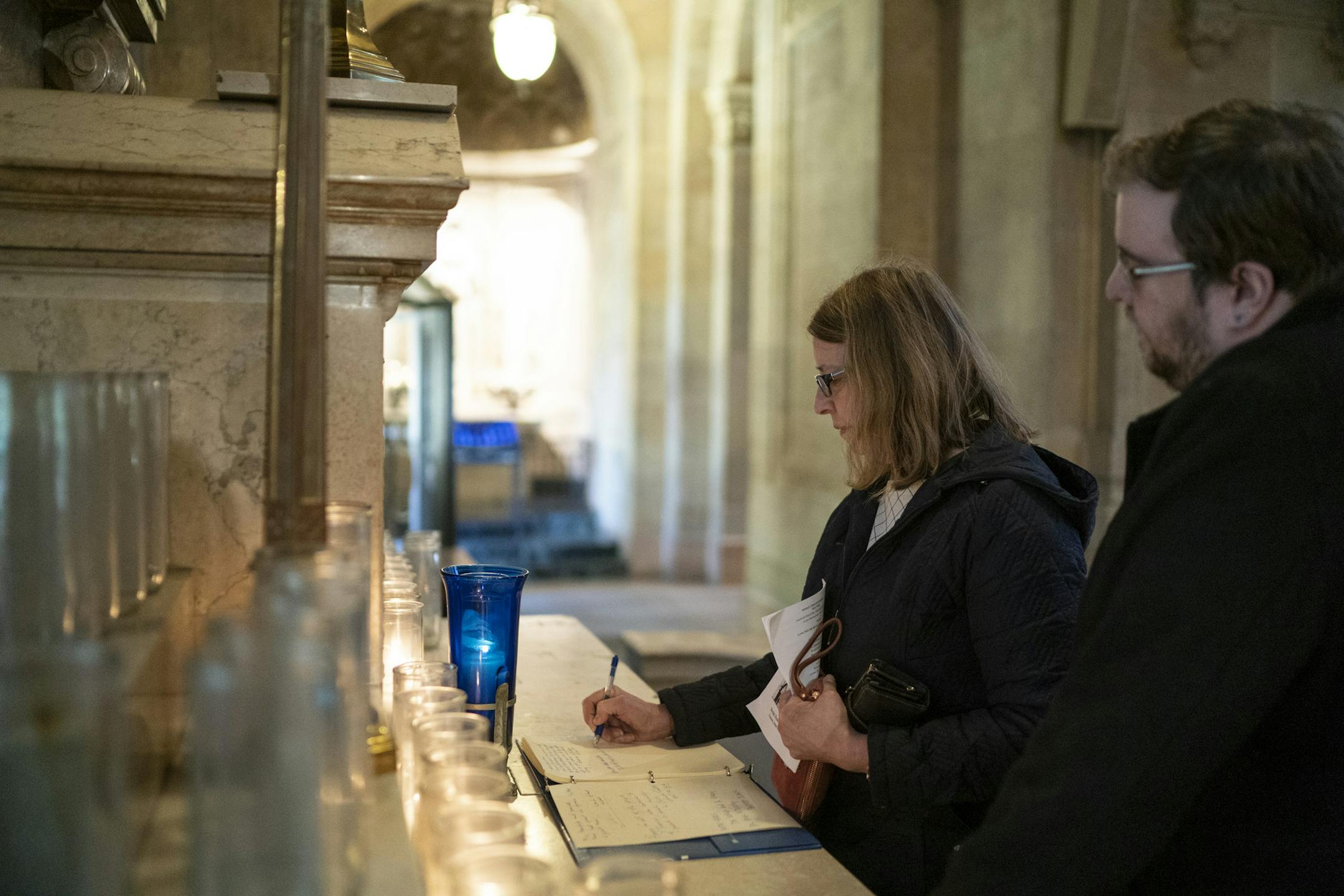Cheryl Miller of Eden Prairie wrote a message in a book of prayers for Notre Dame on the Altar of the Sacred Heart at Basilica of St. Mary in Minneapolis, Minn., on Tuesday, April 16, 2019. At right is her son Alex Miller. Cheryl Miller, who is a hospice and palliative care chaplin and is not a catholic, said she felt she had to make the journey to the Basilica for a special mass for Notre Dame to wish people God's blessing and peace. She and her son once visited Notre Dame 15 years ago on Good