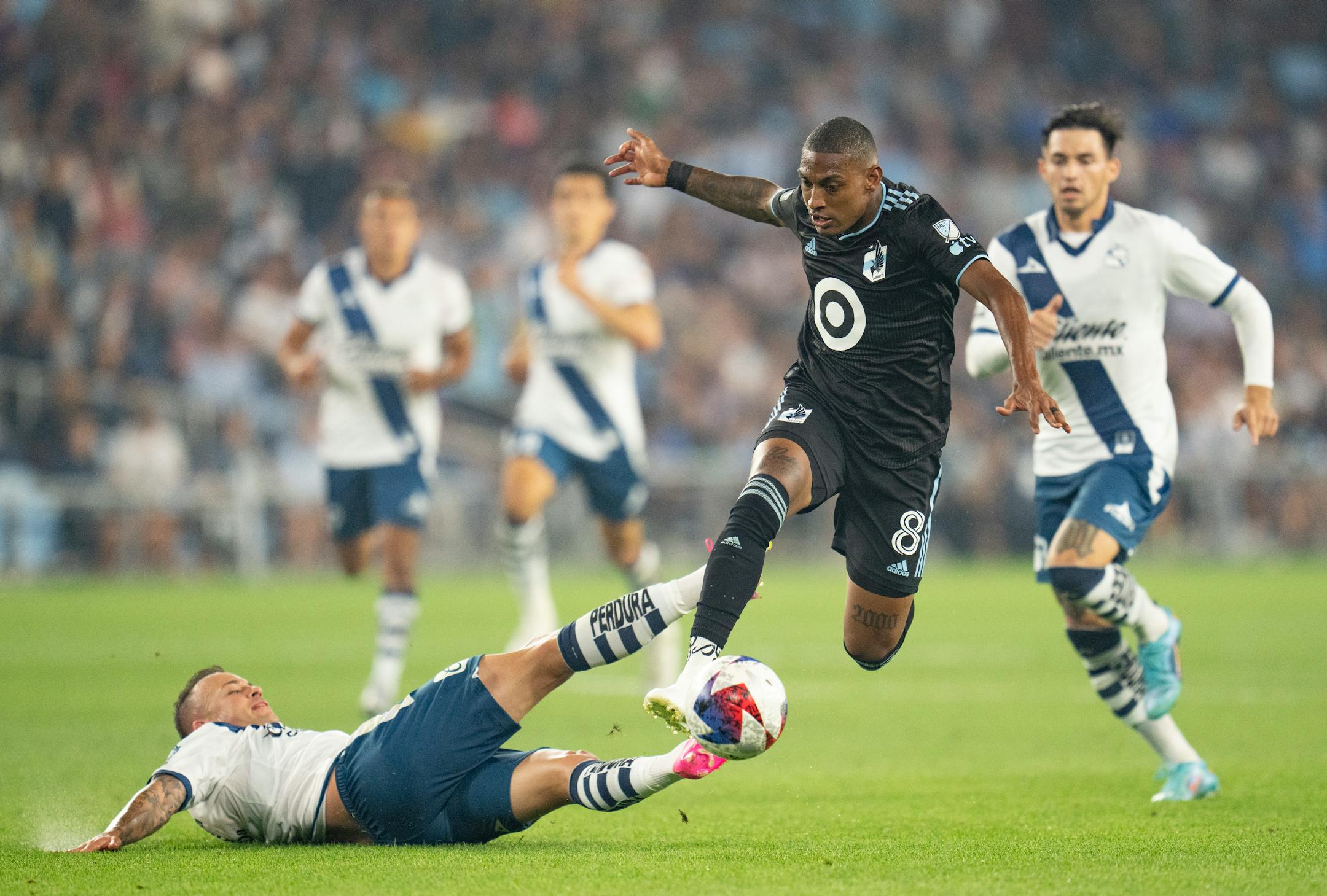 Minnesota United midfielder Joseph Rosales (8) jumps over a slide tackle by Puebla forward Gustavo Henrique Ferrareis in the second half.