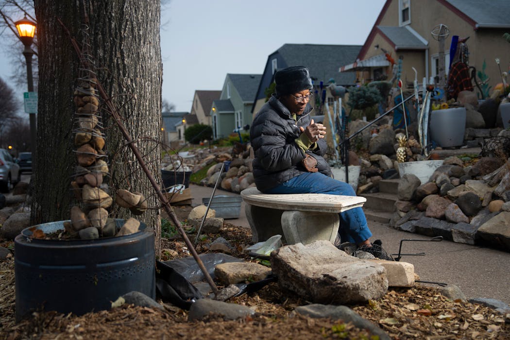 Iris Logan sits on a bench on the boulevard in front of her St. Paul home that the city is ordering her to remove, along with dozens of rocks. She enjoys sitting there and looking at her elaborate sculpture and mosaic front garden.
