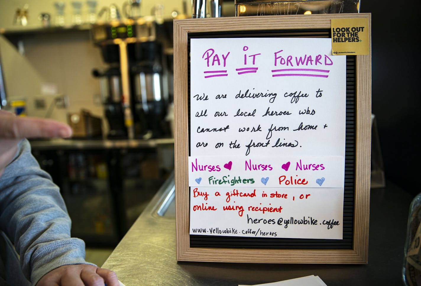 A sign in Yellow Bike coffee shop implores customers to pay it forward in the community. ]
ALEX KORMANN &#x2022; alex.kormann@startribune.com MidCoast Catering and Yellow Bike coffee shop banded together with a judge to raise $13,000 to deliver meals to healthcare workers. They also put together small packages of food and coffee to bring to local healthcare workers, including those that work in assisted living homes.