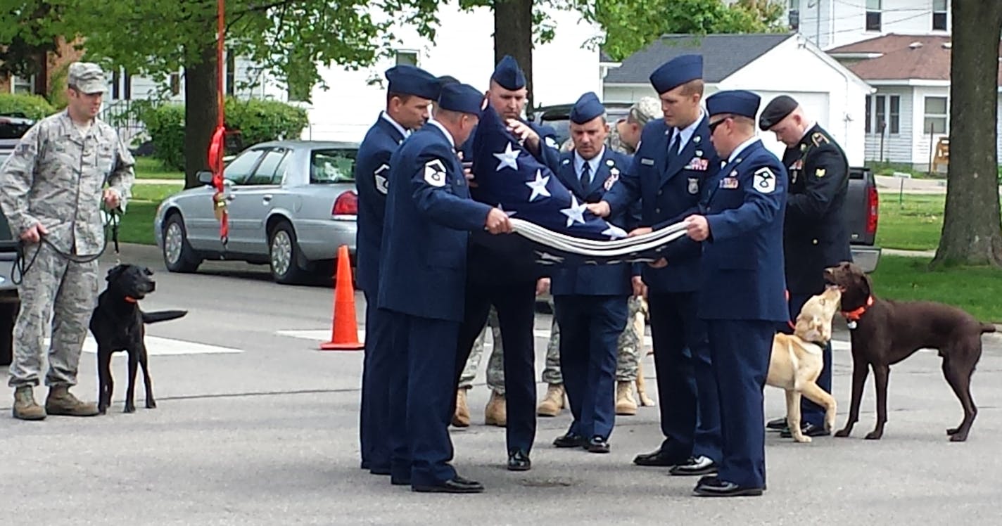 Soldiers folded an American flag flown outside of Stacy Dvorak's funeral, while others with dogs they received from Dvorak under her Operation Puppies for Soldiers program watch. Photo courtesy Andrea Neville