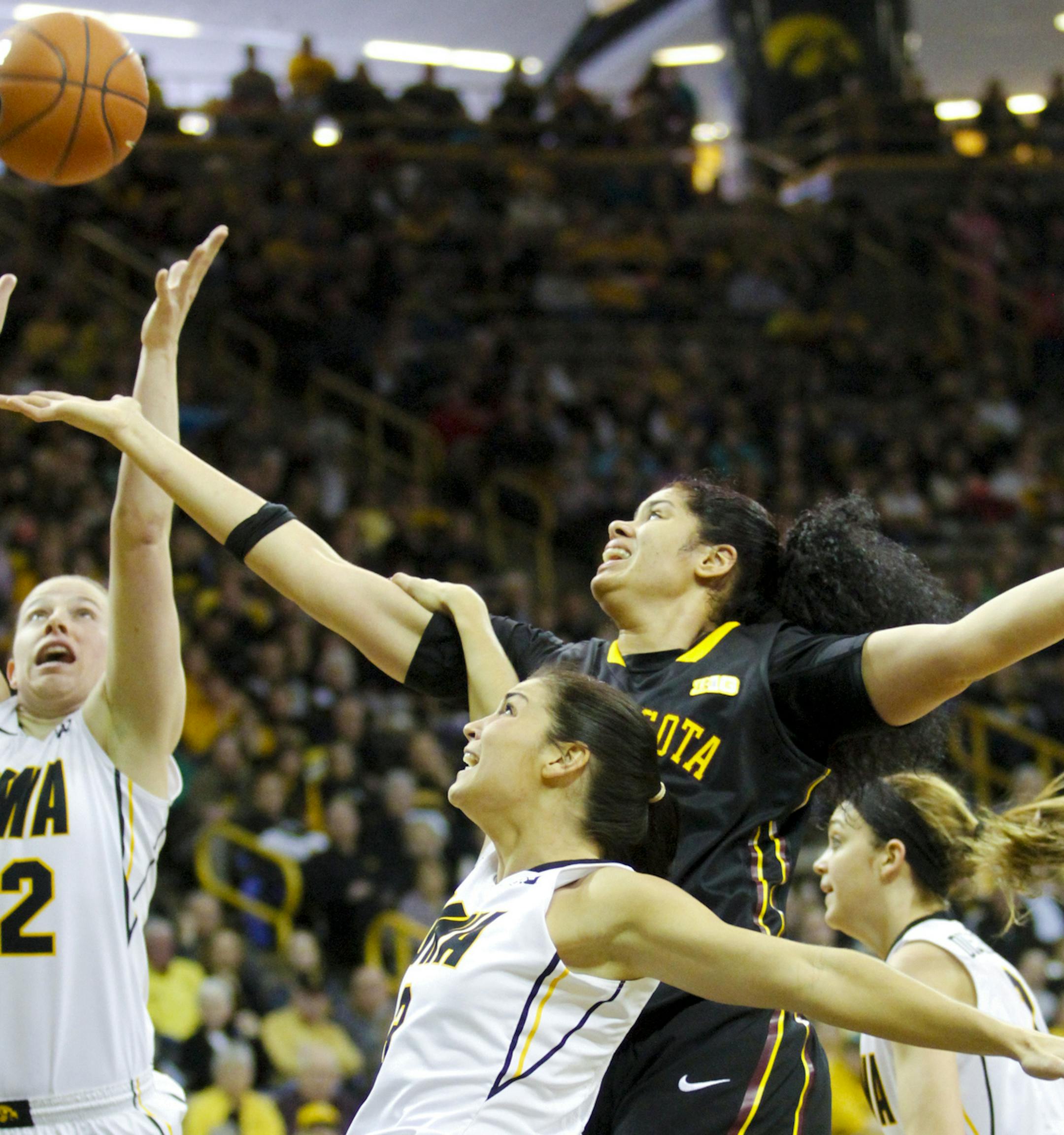 Minnesota center Amanda Zahui, center top, battles for a rebound with Iowa's Samantha Logic (22) and Claire Till (3) during the first half of an NCAA college basketball game, Sunday, March 1, 2015, in Iowa City, Iowa. (AP Photo/Matthew Holst)