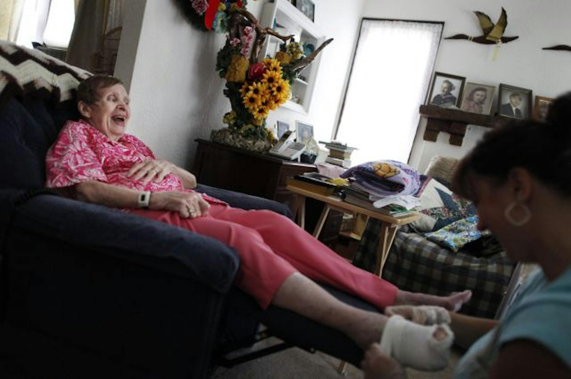 At her home in South Minneapolis, Lorraine Anderson, 82, cracks a couple of jokes as home health aide Judy Chen helps her with some orthopedic socks that help keep the swelling down in her feet.