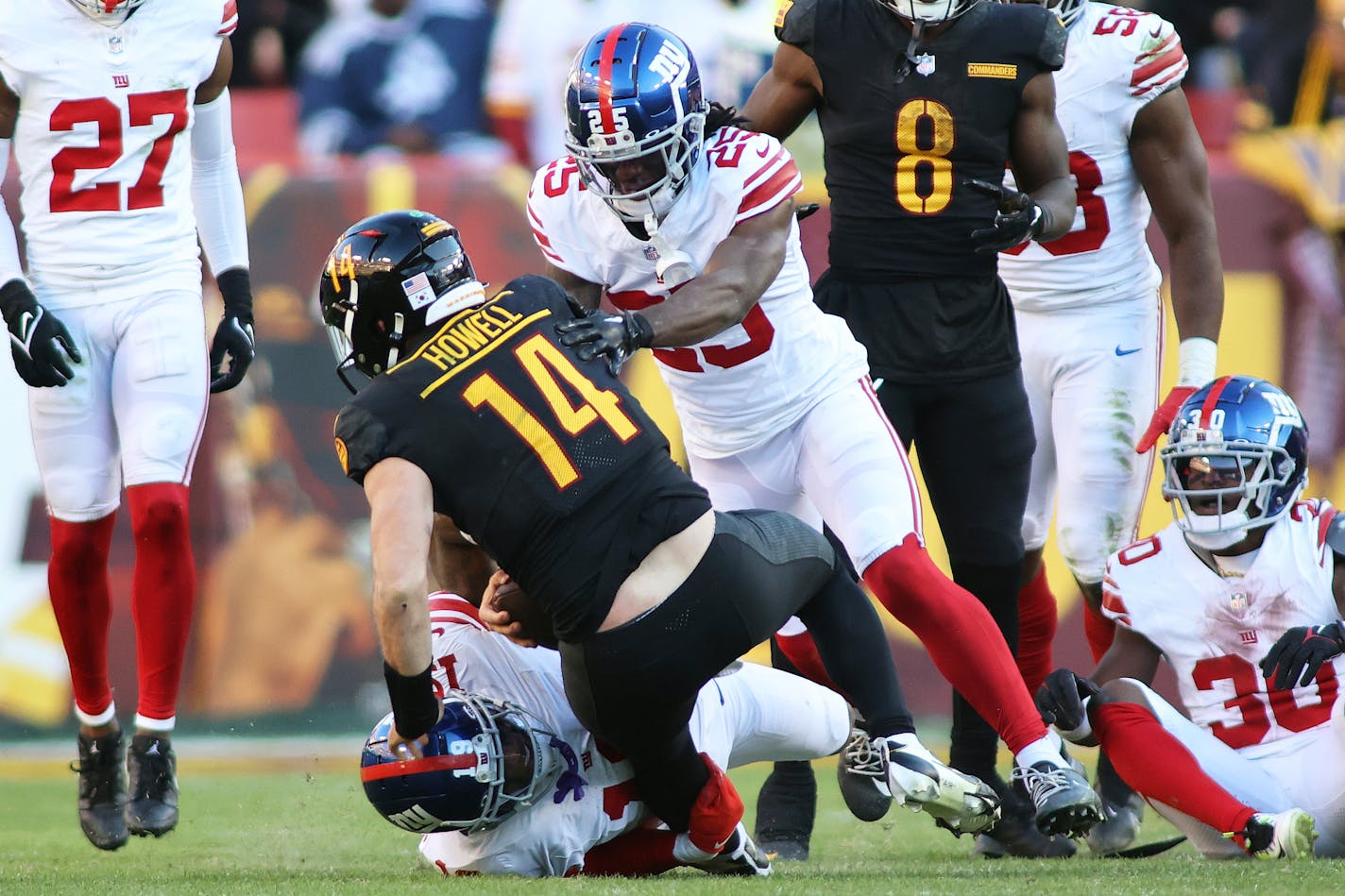 Washington Commanders quarterback Sam Howell (14) gets taken down for sack by multiple New York Giants defenders during an NFL football game, Sunday, November 19, 2023 in Landover, Md. (AP Photo/Daniel Kucin Jr.)