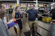 Travis Heins hands over hard cider to his wife, Kelsey Heins, at Chicone&#x2019;s Liquor Mart in Hudson, Wis., on Monday, a day after Sunday liquor sa