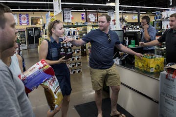 Travis Heins hands over hard cider to his wife, Kelsey Heins, at Chicone&#x2019;s Liquor Mart in Hudson, Wis., on Monday, a day after Sunday liquor sa