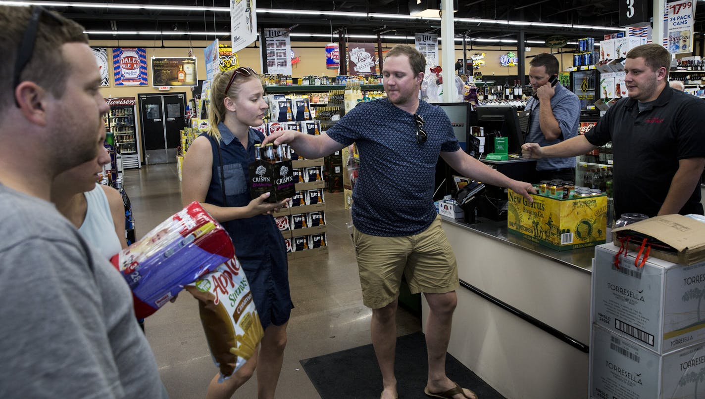 Travis Heins hands over hard cider to his wife, Kelsey Heins, at Chicone&#x2019;s Liquor Mart in Hudson, Wis., on Monday, a day after Sunday liquor sales began in neighboring Minnesota. Officials at the store say they saw little impact while other stores in the area say sales were down..