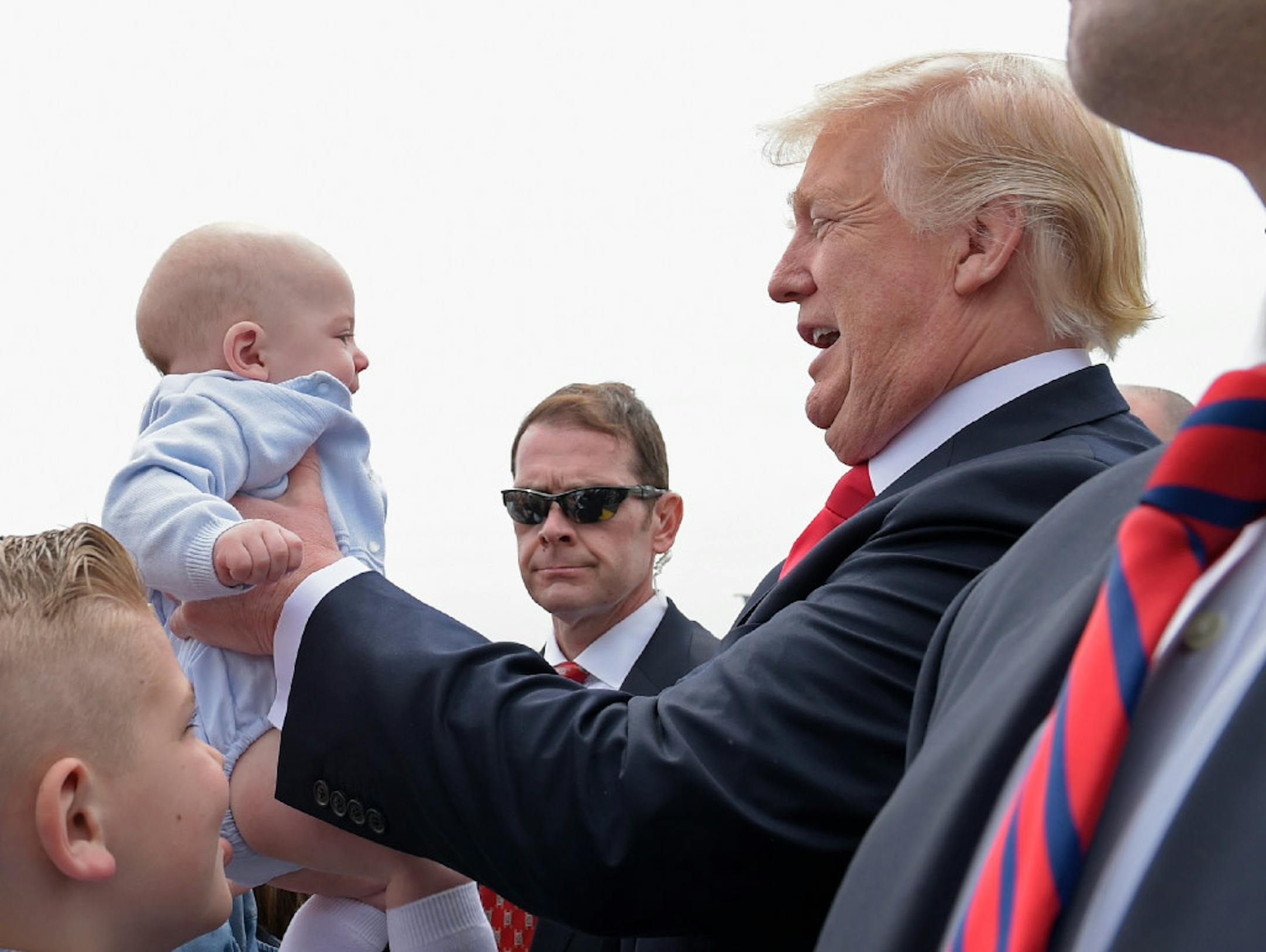 President Donald Trump picks up a baby as he greets people Tuesday after arriving on Air Force One in Milwaukee.